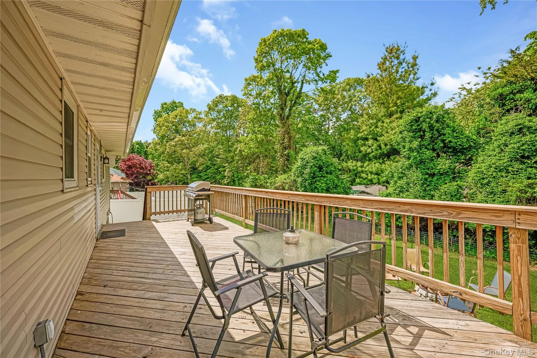 Expansive wood deck with natural wood railings, exterior siding, and a lush green backdrop Expansive wood deck with natural wood railings, exterior siding, and a lush green backdrop