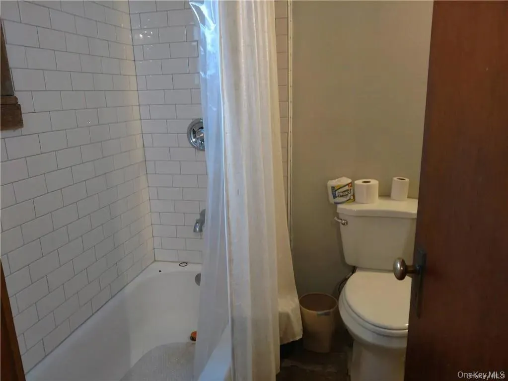 Bathroom featuring shower / bath combo and toilet Bathroom featuring shower / bath combo and toilet