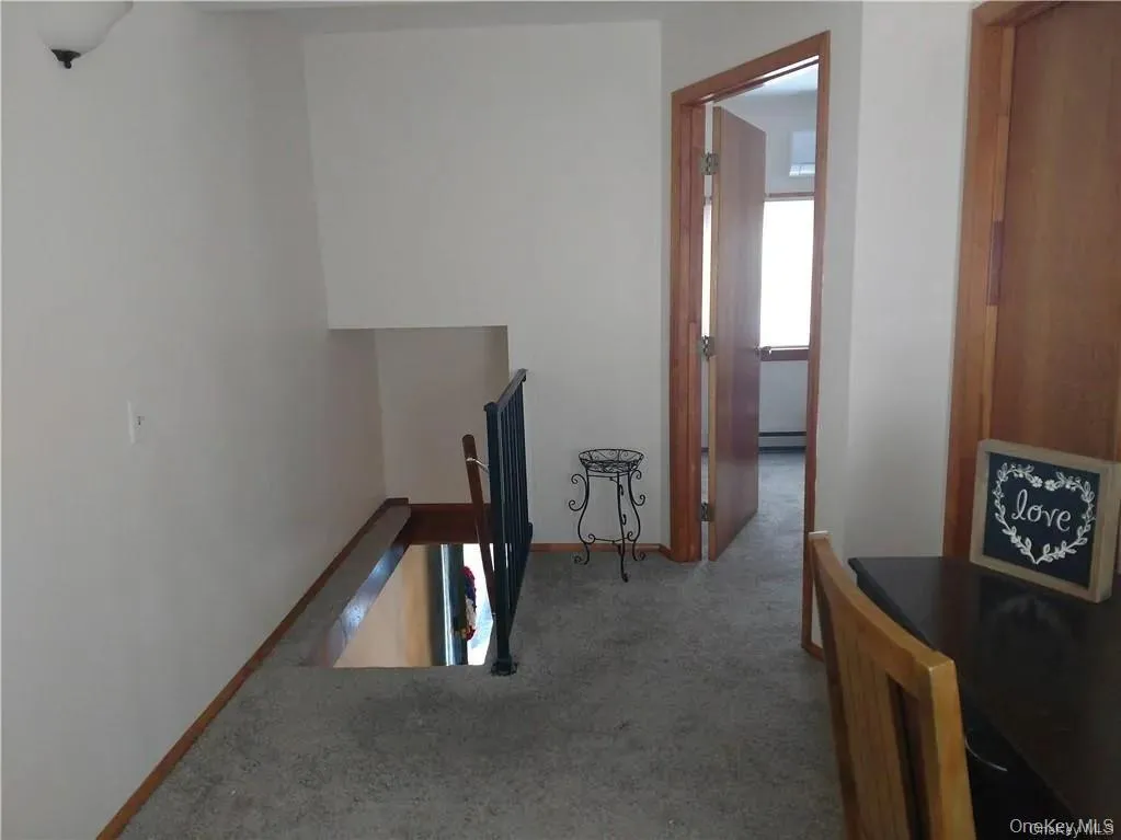 Corridor with baseboards, carpet floors, and an upstairs landing Corridor with baseboards, carpet floors, and an upstairs landing