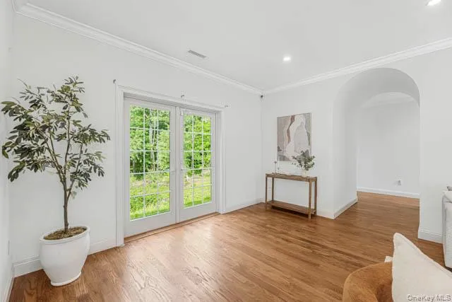 Spacious living area featuring hardwood flooring, a fireplace with a white mantel, recessed lighting, and a prominent Spacious living area featuring hardwood flooring, a fireplace with a white mantel, recessed lighting, and a prominent