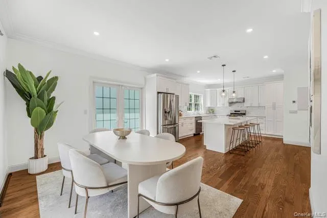 Open-concept dining area featuring hard surface flooring, white walls, and double French doors Open-concept dining area featuring hard surface flooring, white walls, and double French doors