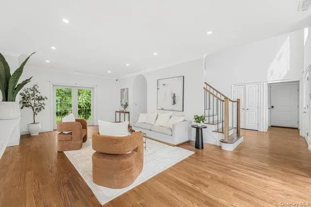 Spacious living area featuring wood-finish flooring, recessed lighting, and a double-height ceiling Spacious living area featuring wood-finish flooring, recessed lighting, and a double-height ceiling