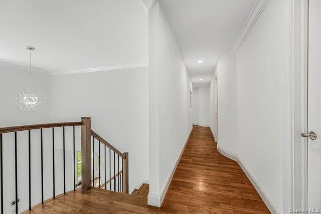 Upper landing featuring wood-finish flooring, a contemporary chandelier, and a hallway with recessed lighting Upper landing featuring wood-finish flooring, a contemporary chandelier, and a hallway with recessed lighting