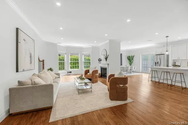 Open-concept living area with hardwood flooring, recessed lighting, and crown molding Open-concept living area with hardwood flooring, recessed lighting, and crown molding