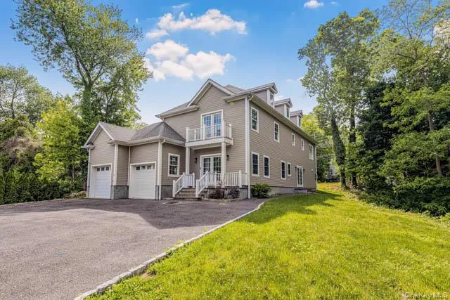 Contemporary residence featuring horizontal siding, a prominent two-car garage, and a spacious paved driveway Contemporary residence featuring horizontal siding, a prominent two-car garage, and a spacious paved driveway