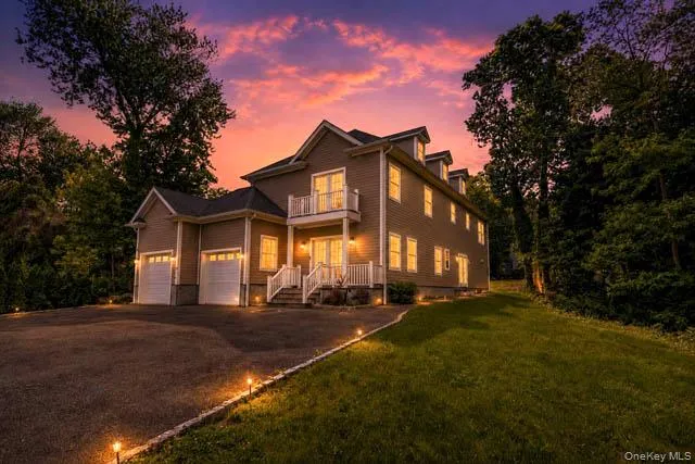 Contemporary property featuring a neutral-toned exterior, a two-car garage, a second-story balcony, and multiple dormer windows Contemporary property featuring a neutral-toned exterior, a two-car garage, a second-story balcony, and multiple dormer windows