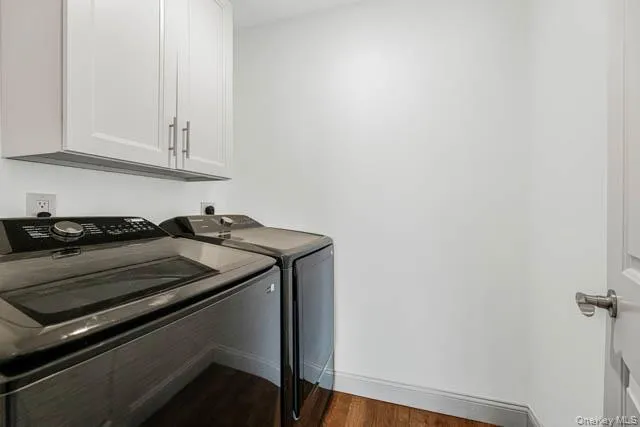 Dedicated laundry area featuring overhead white cabinetry with brushed nickel hardware and wood-finish flooring Dedicated laundry area featuring overhead white cabinetry with brushed nickel hardware and wood-finish flooring