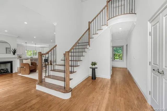 Two-story entry featuring hardwood flooring, a curved staircase with wood handrails and wrought iron balusters, recessed lighting, and white paneled doors Two-story entry featuring hardwood flooring, a curved staircase with wood handrails and wrought iron balusters, recessed lighting, and white paneled doors