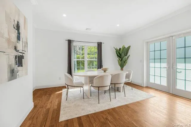 Spacious dining area featuring wood-finish flooring, white walls, and recessed lighting Spacious dining area featuring wood-finish flooring, white walls, and recessed lighting