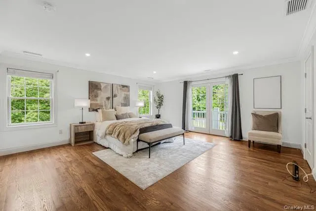Spacious room featuring wood-finish flooring, white walls, and recessed lighting Spacious room featuring wood-finish flooring, white walls, and recessed lighting