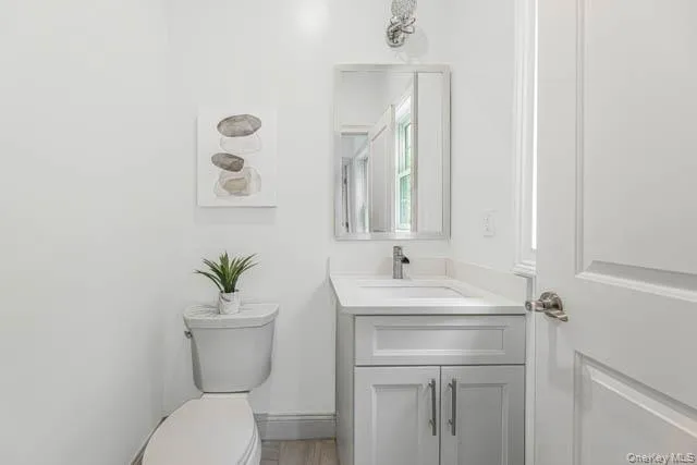 Powder room featuring a single vanity with a white countertop, chrome faucet, and a wall-mounted mirror Powder room featuring a single vanity with a white countertop, chrome faucet, and a wall-mounted mirror