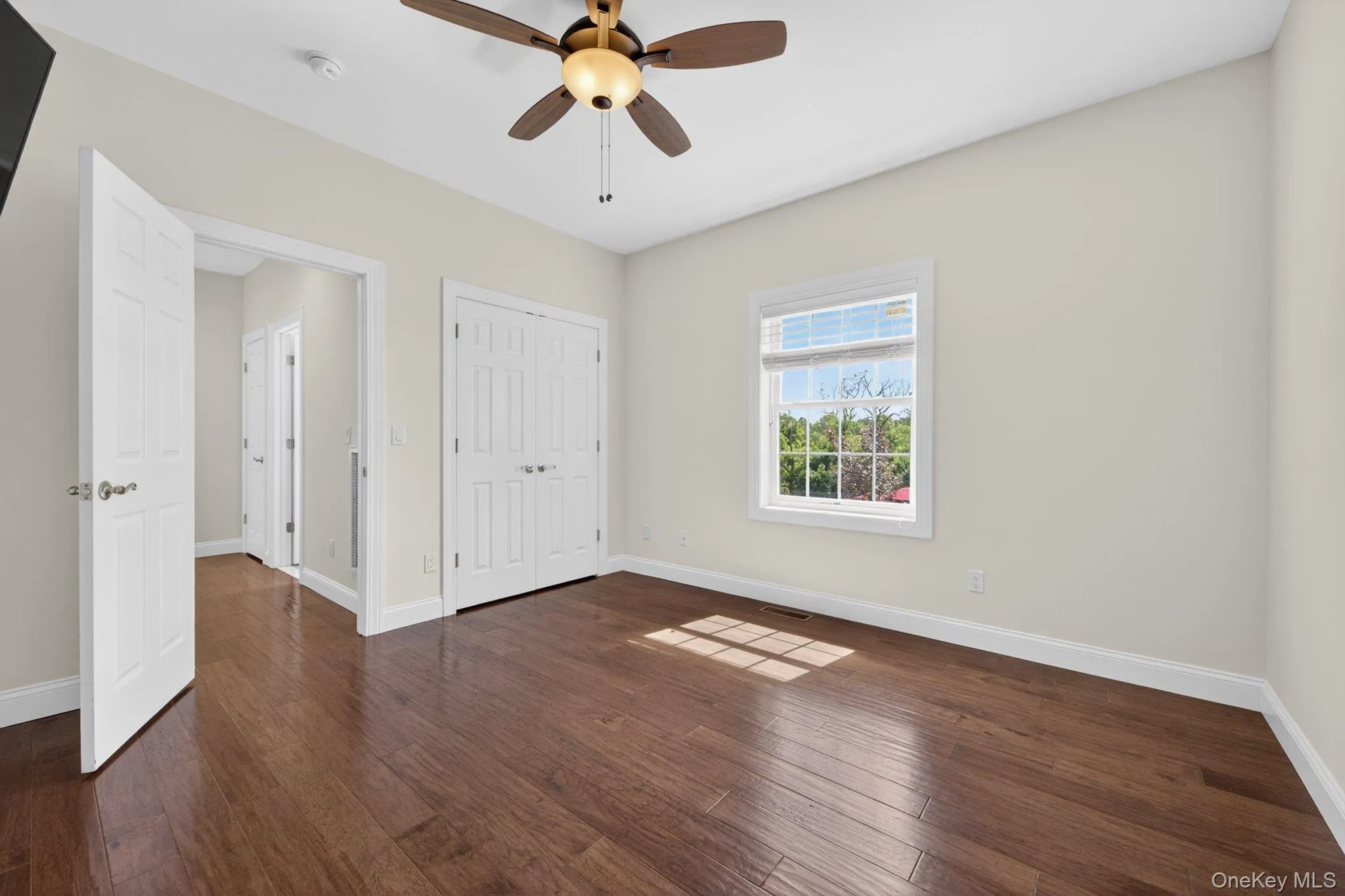 Bedroom featuring wood-finish flooring, a ceiling fan with integrated lighting, and a window with blinds Bedroom featuring wood-finish flooring, a ceiling fan with integrated lighting, and a window with blinds