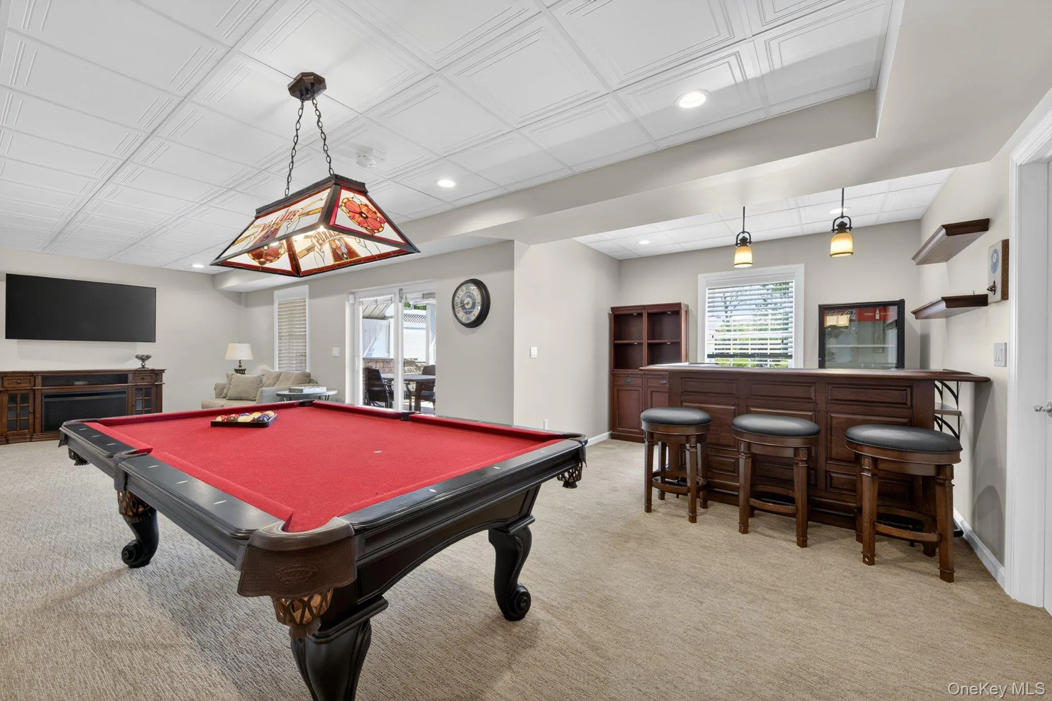 Spacious recreation room featuring a red-felt pool table, built-in wet bar with pendant lighting, and recessed ceiling lights Spacious recreation room featuring a red-felt pool table, built-in wet bar with pendant lighting, and recessed ceiling lights
