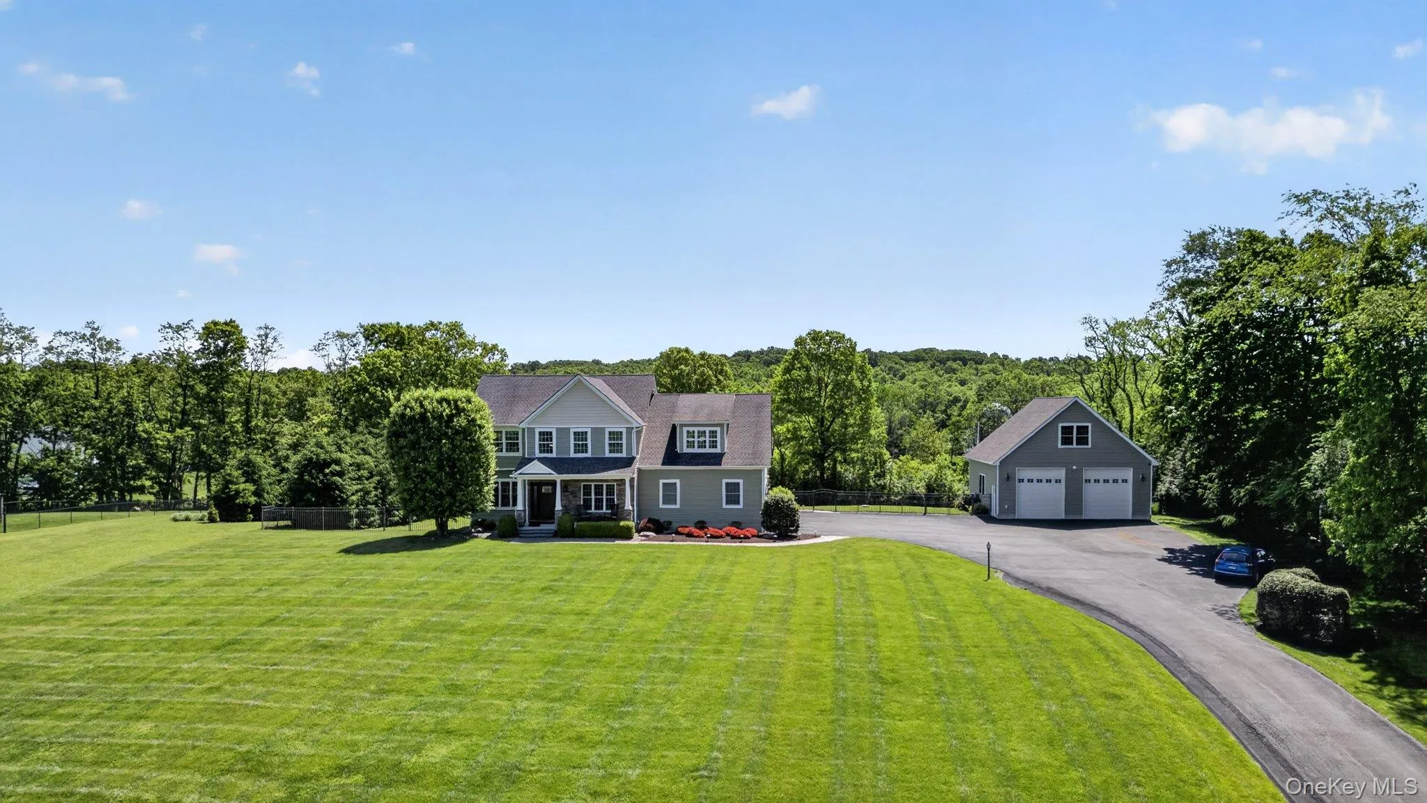 Expansive green lawn surrounds a two-story residence with light gray siding and dark roof Expansive green lawn surrounds a two-story residence with light gray siding and dark roof