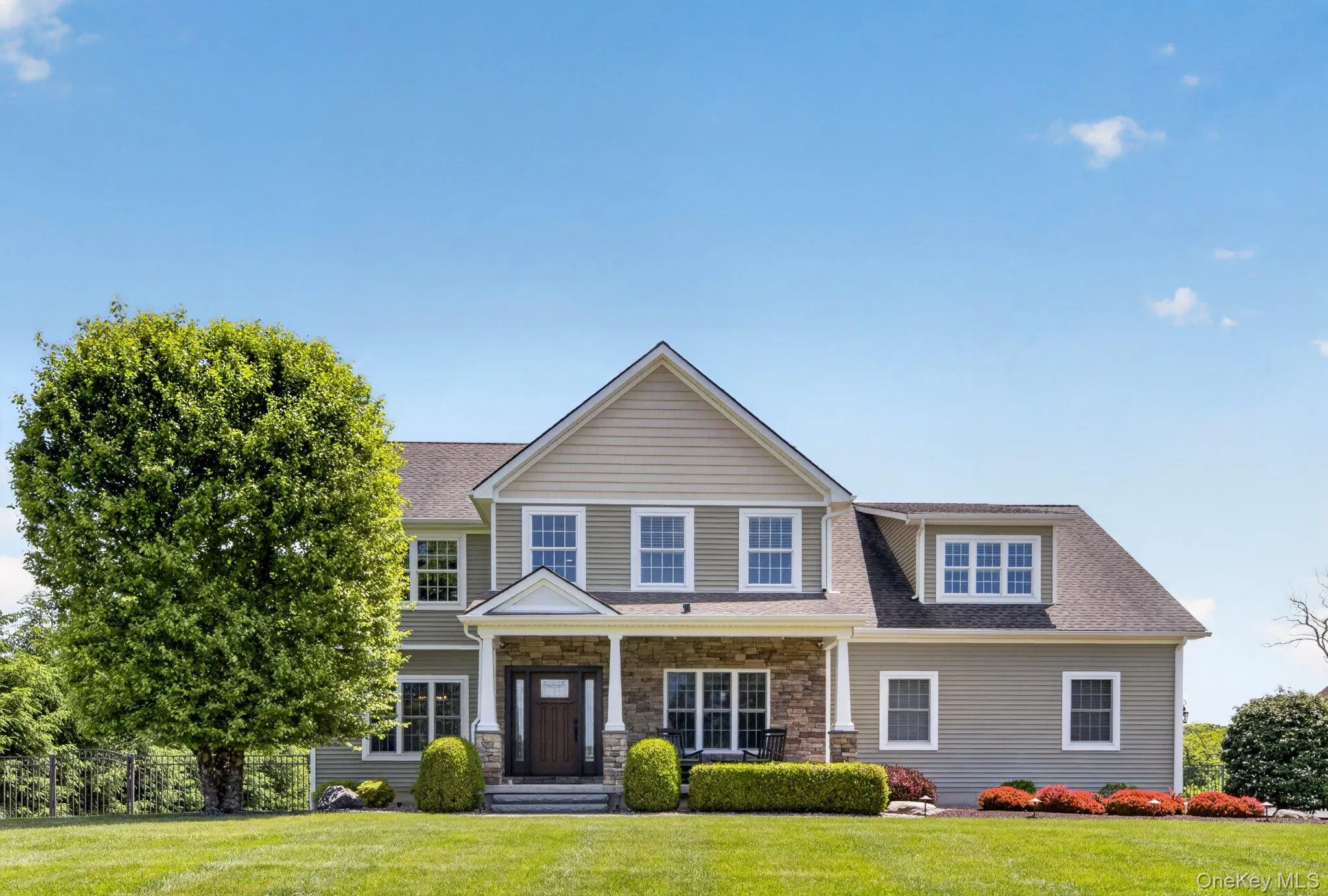 Expansive green lawn with a two-story residence featuring light green siding and stone accents Expansive green lawn with a two-story residence featuring light green siding and stone accents