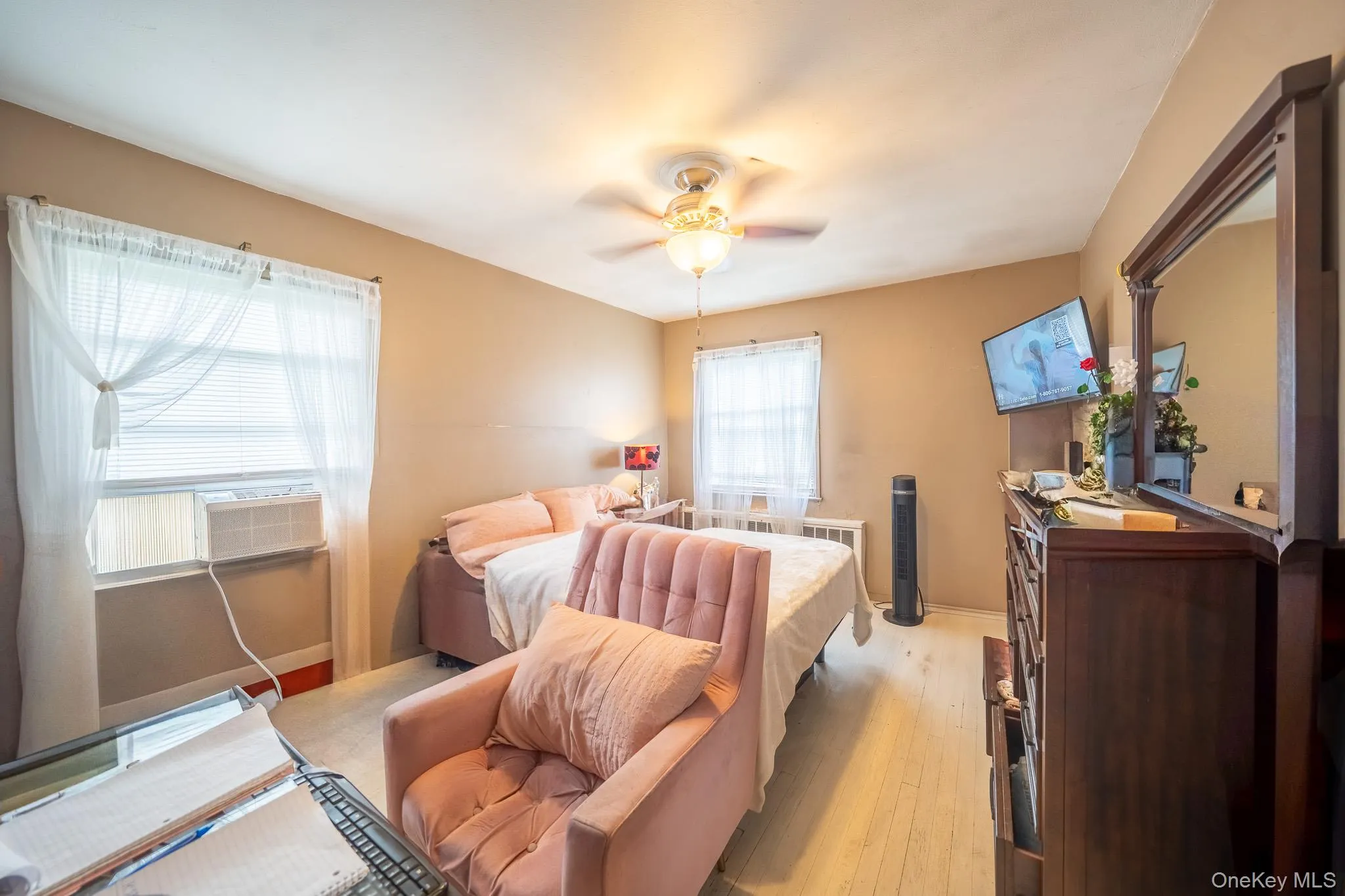 Bedroom with light wood-style floors, a ceiling fan, and cooling unit Bedroom with light wood-style floors, a ceiling fan, and cooling unit