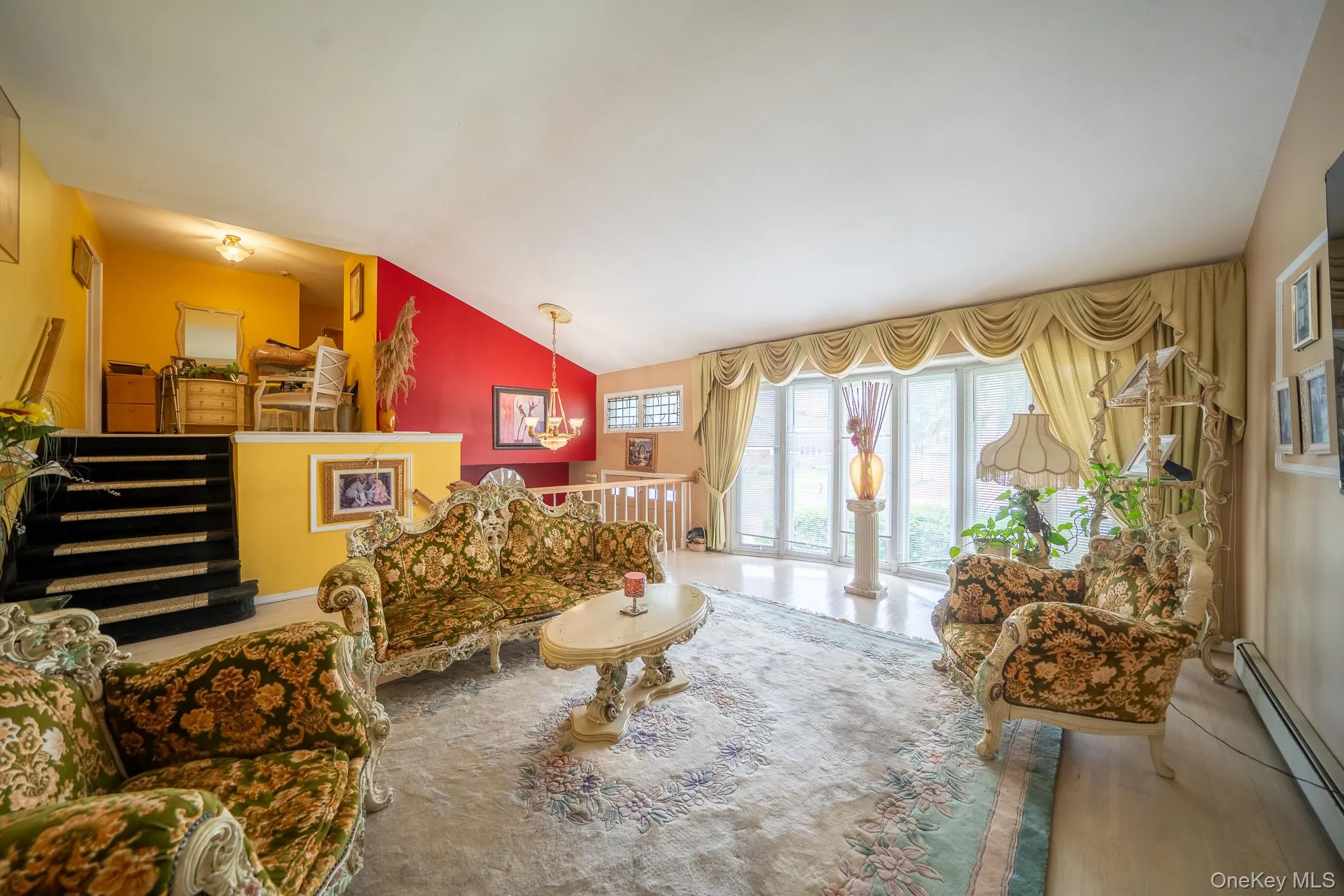 Living area with a baseboard heating unit, vaulted ceiling, a chandelier, and wood finished floors Living area with a baseboard heating unit, vaulted ceiling, a chandelier, and wood finished floors