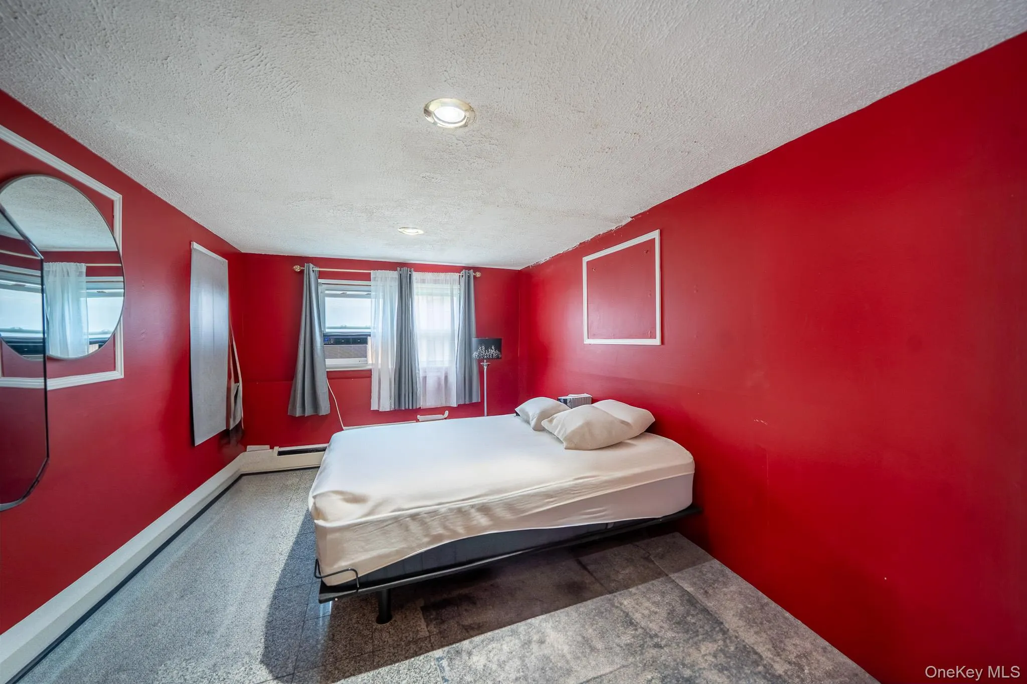 Bedroom with a textured ceiling and a baseboard radiator Bedroom with a textured ceiling and a baseboard radiator