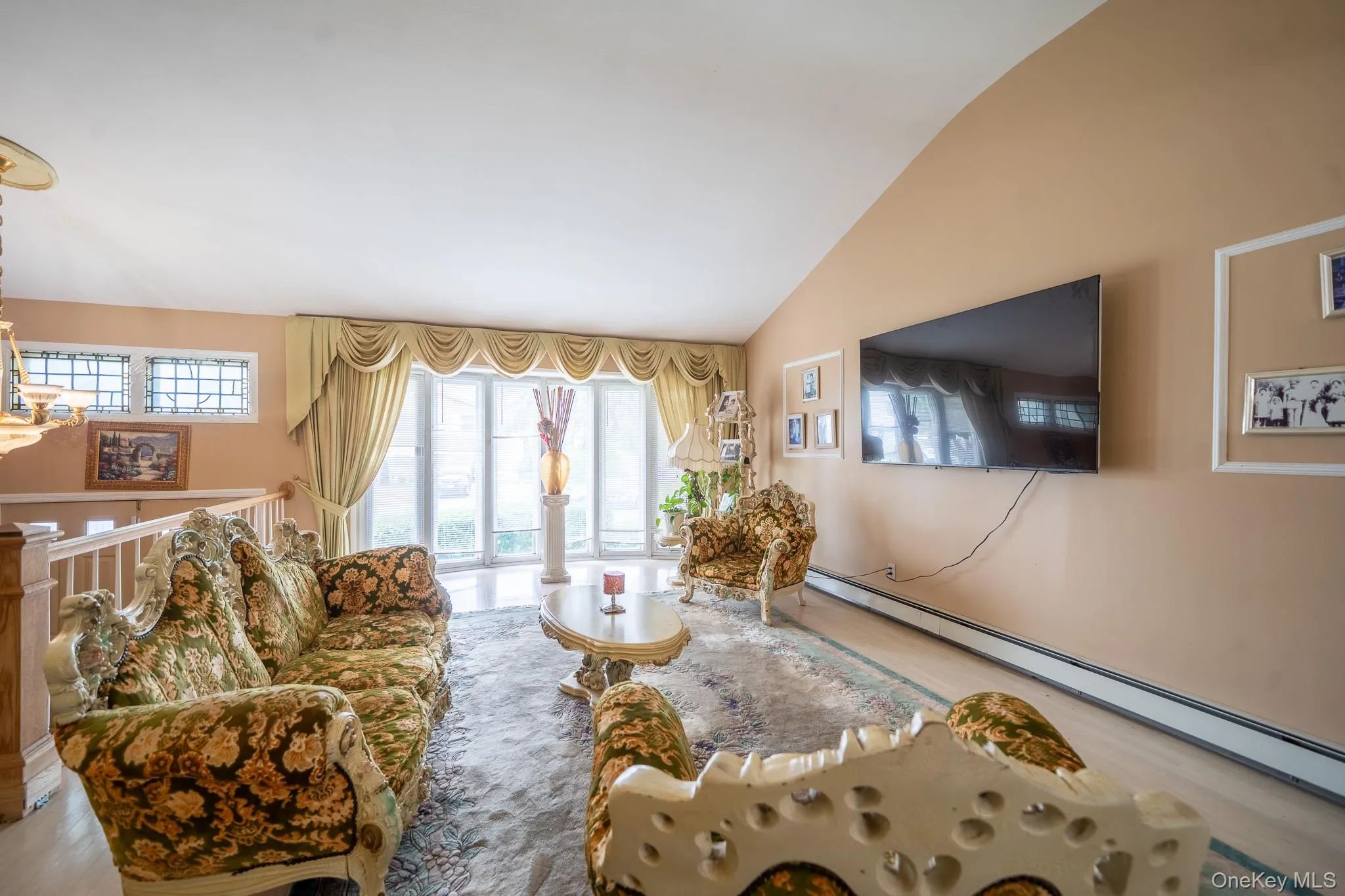 Living room with vaulted ceiling, healthy amount of natural light, baseboard heating, and wood finished floors Living room with vaulted ceiling, healthy amount of natural light, baseboard heating, and wood finished floors