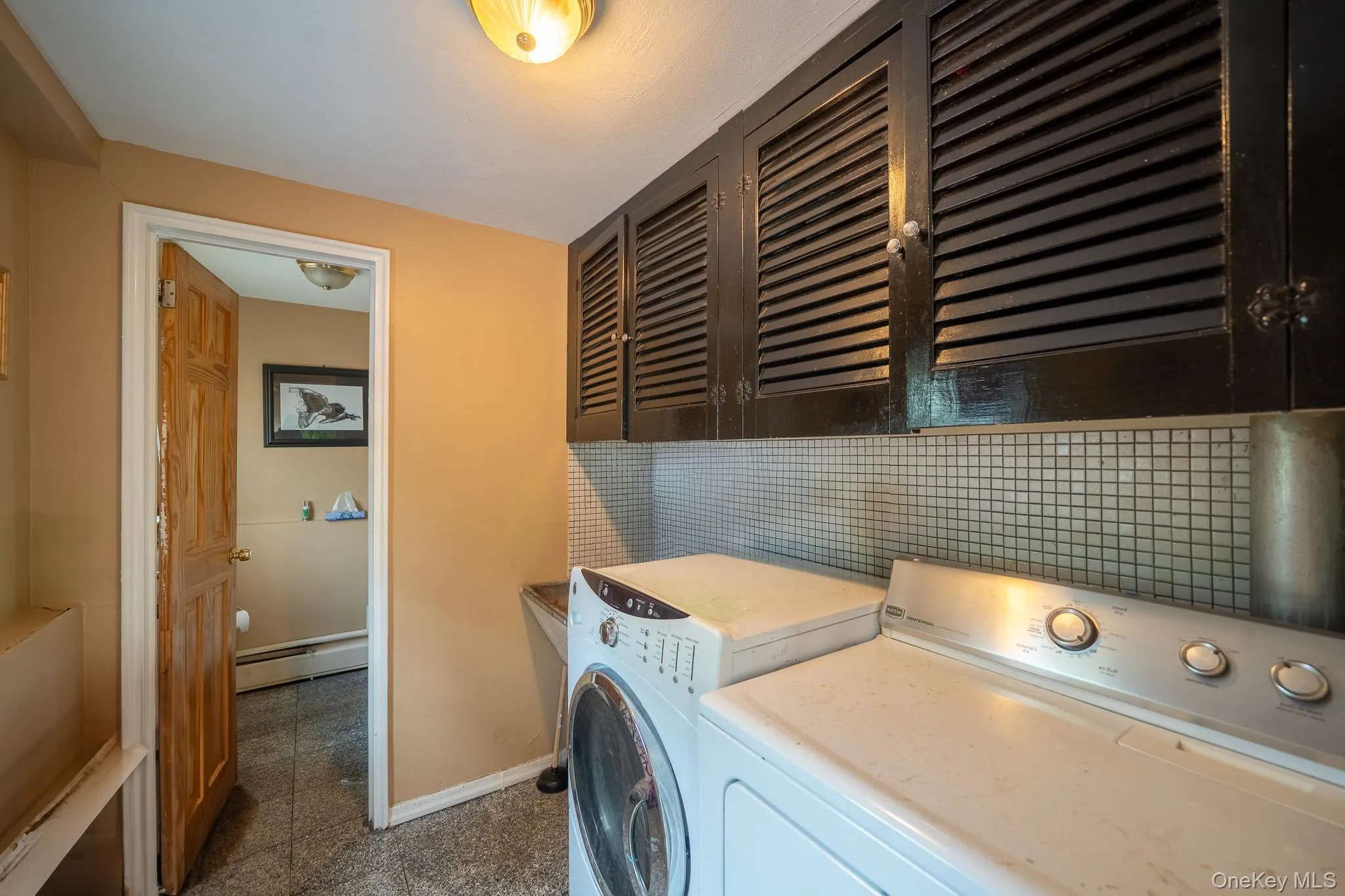 Washroom featuring a baseboard heating unit, cabinet space, and washer and dryer Washroom featuring a baseboard heating unit, cabinet space, and washer and dryer
