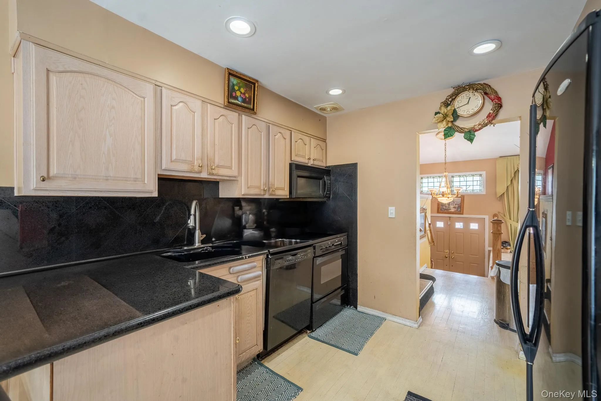 Kitchen with black appliances, light brown cabinets, tasteful backsplash, light wood-style floors, and recessed lighting Kitchen with black appliances, light brown cabinets, tasteful backsplash, light wood-style floors, and recessed lighting
