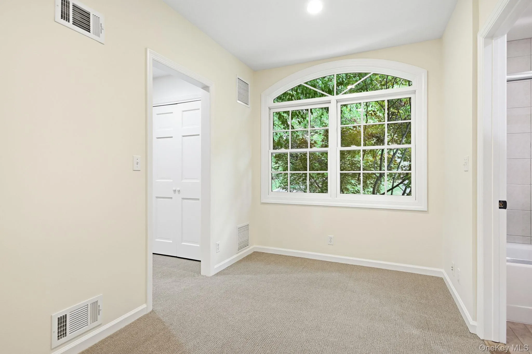 Second en-suite (same split level up) featuring a sitting room; arched window with grid panes overlooking lush greenery Second en-suite (same split level up) featuring a sitting room; arched window with grid panes overlooking lush greenery