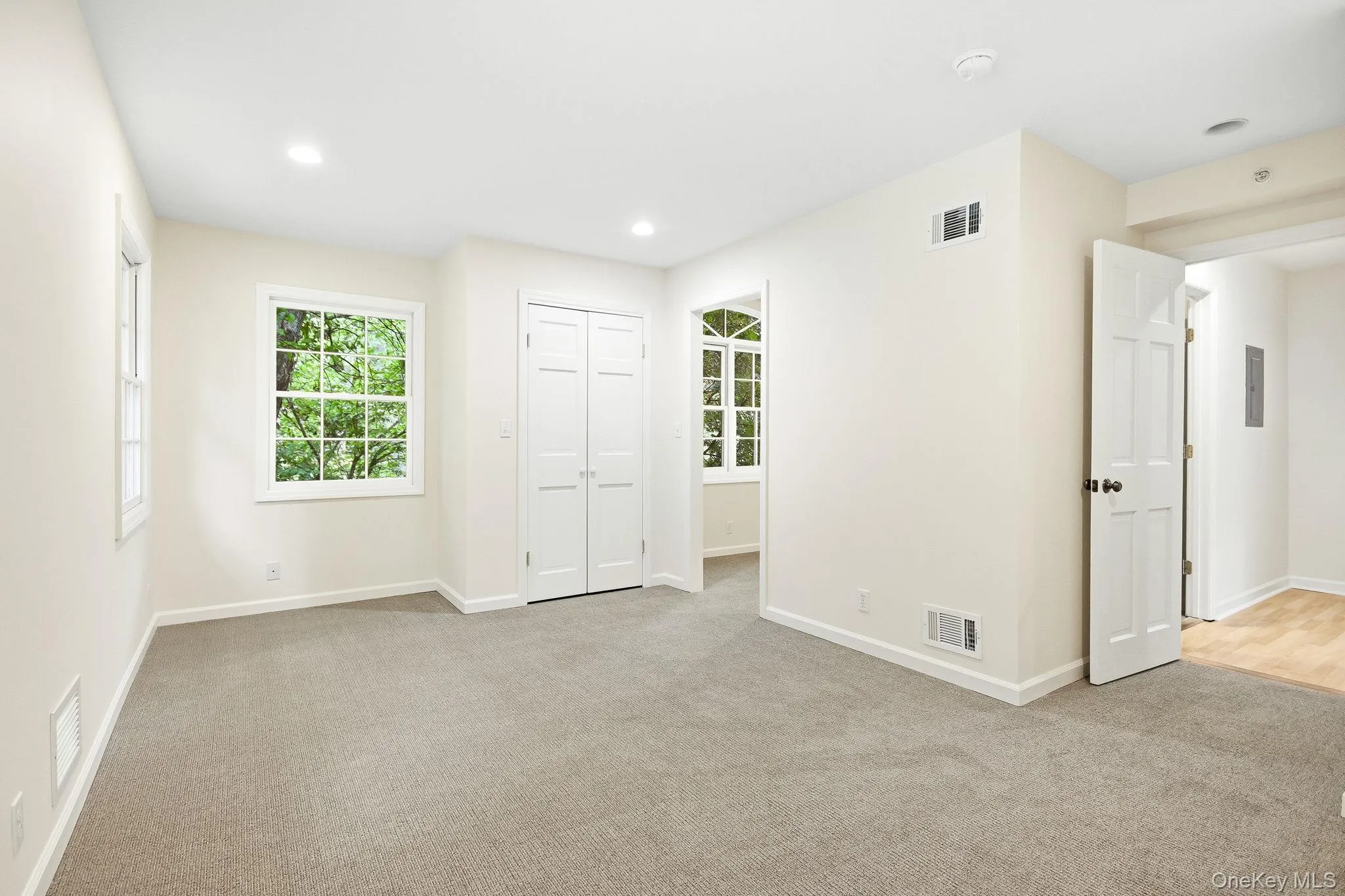 Second en-suite bedroom; carpeted room with recessed lighting, two sash windows, and white bi-fold closet doors Second en-suite bedroom; carpeted room with recessed lighting, two sash windows, and white bi-fold closet doors