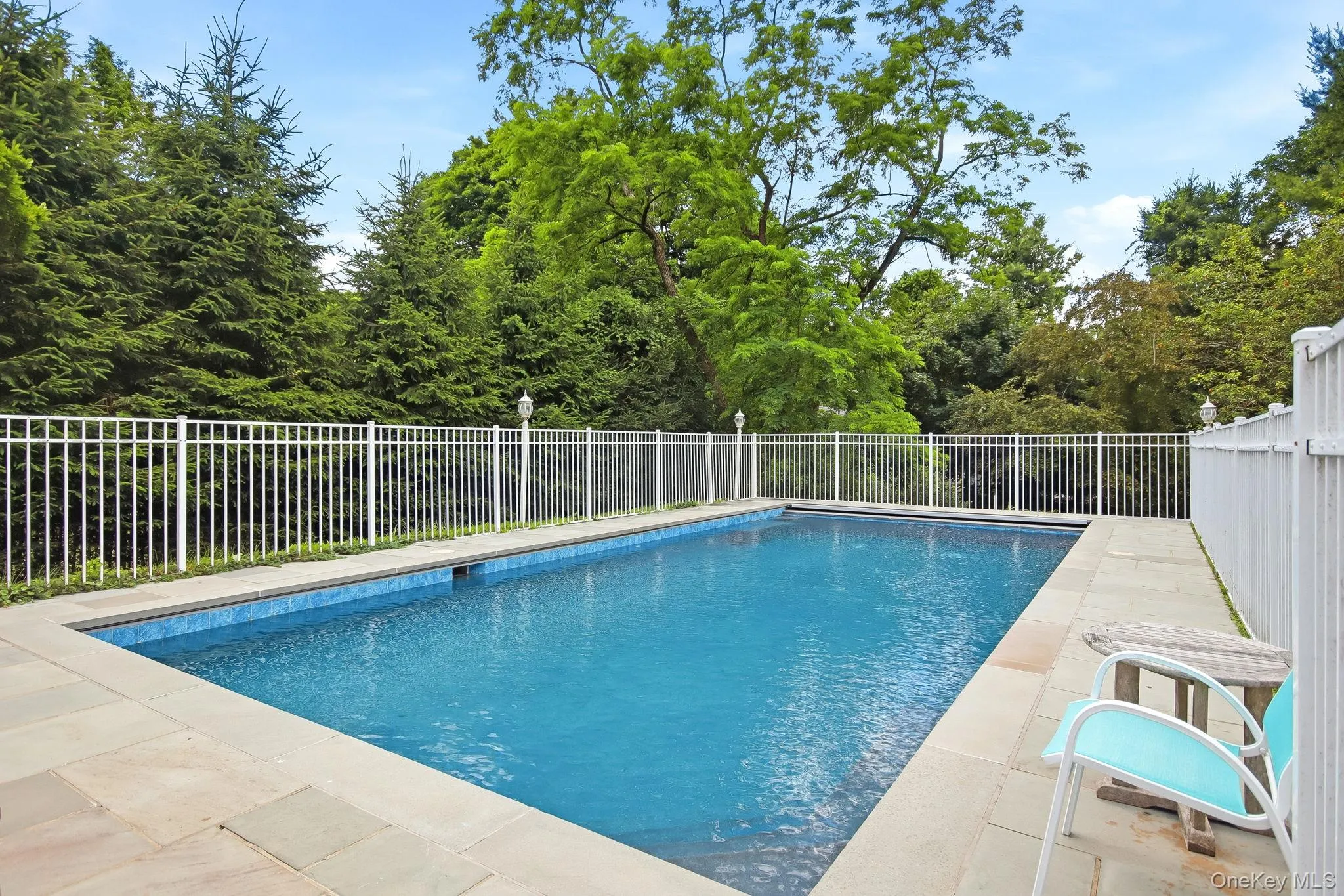 In-ground swimming pool featuring a tiled interior and stone coping In-ground swimming pool featuring a tiled interior and stone coping