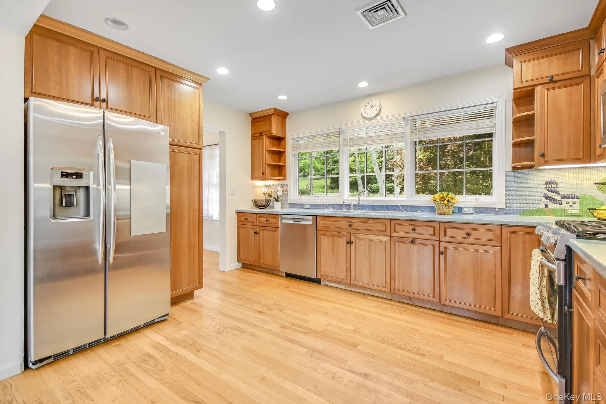 Kitchen featuring wood cabinetry, stainless steel appliances, and hardwood flooring Kitchen featuring wood cabinetry, stainless steel appliances, and hardwood flooring
