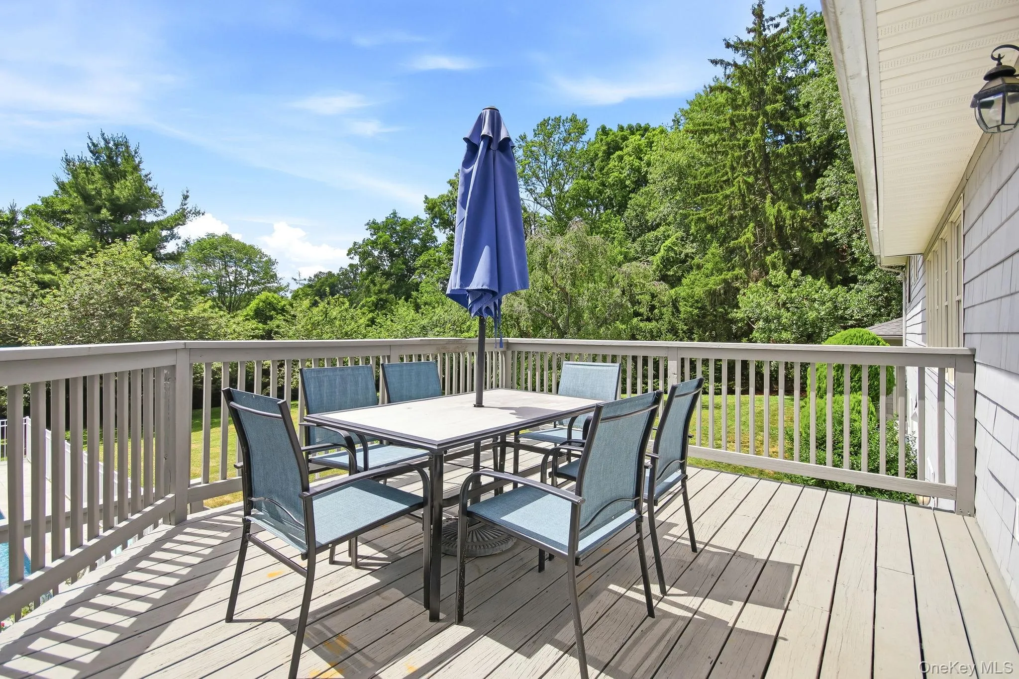 Expansive outdoor deck featuring wood-finish flooring, a full railing system, and exterior wall lighting Expansive outdoor deck featuring wood-finish flooring, a full railing system, and exterior wall lighting