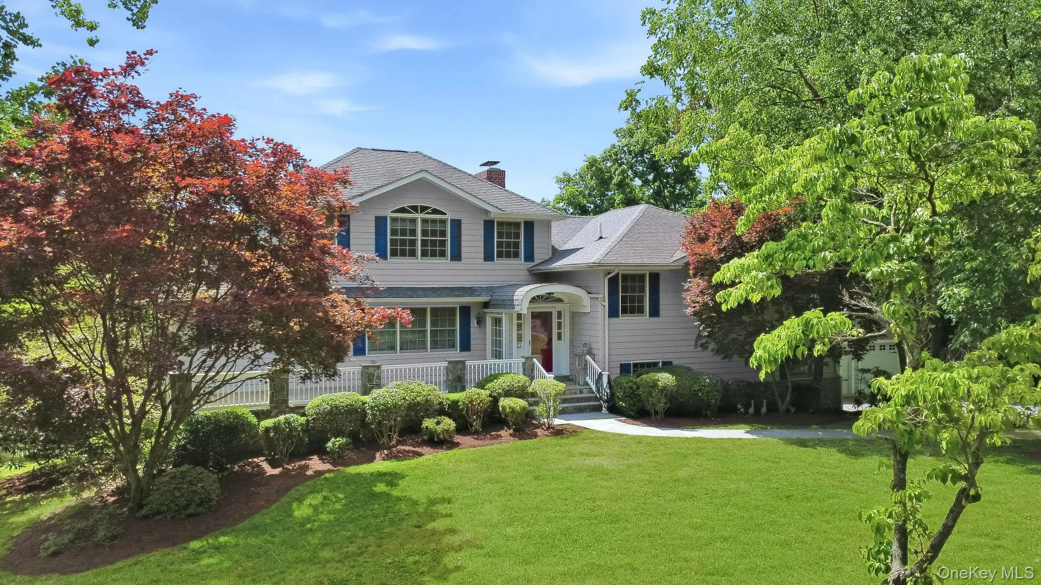 Expansive split-level residence with Colonial charm; featuring light-colored siding, a gabled roofline, and blue window shutters Expansive split-level residence with Colonial charm; featuring light-colored siding, a gabled roofline, and blue window shutters