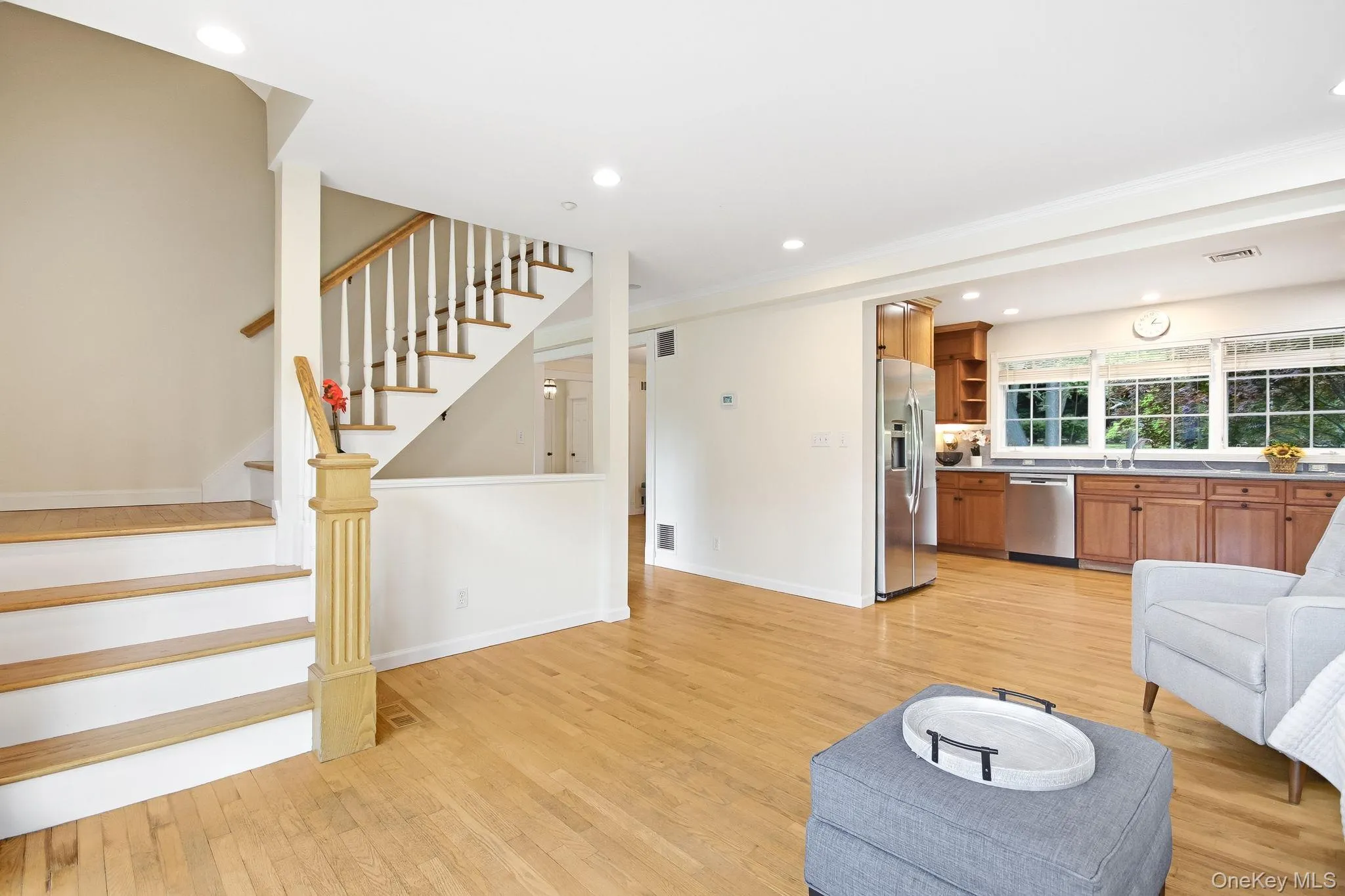 Family room alternate view; hardwood flooring spans this room featuring a staircase with white risers and a light wood handrail which leads to 2 upstairs bedrooms; open flow to kitchen and living room Family room alternate view; hardwood flooring spans this room featuring a staircase with white risers and a light wood handrail which leads to 2 upstairs bedrooms; open flow to kitchen and living room