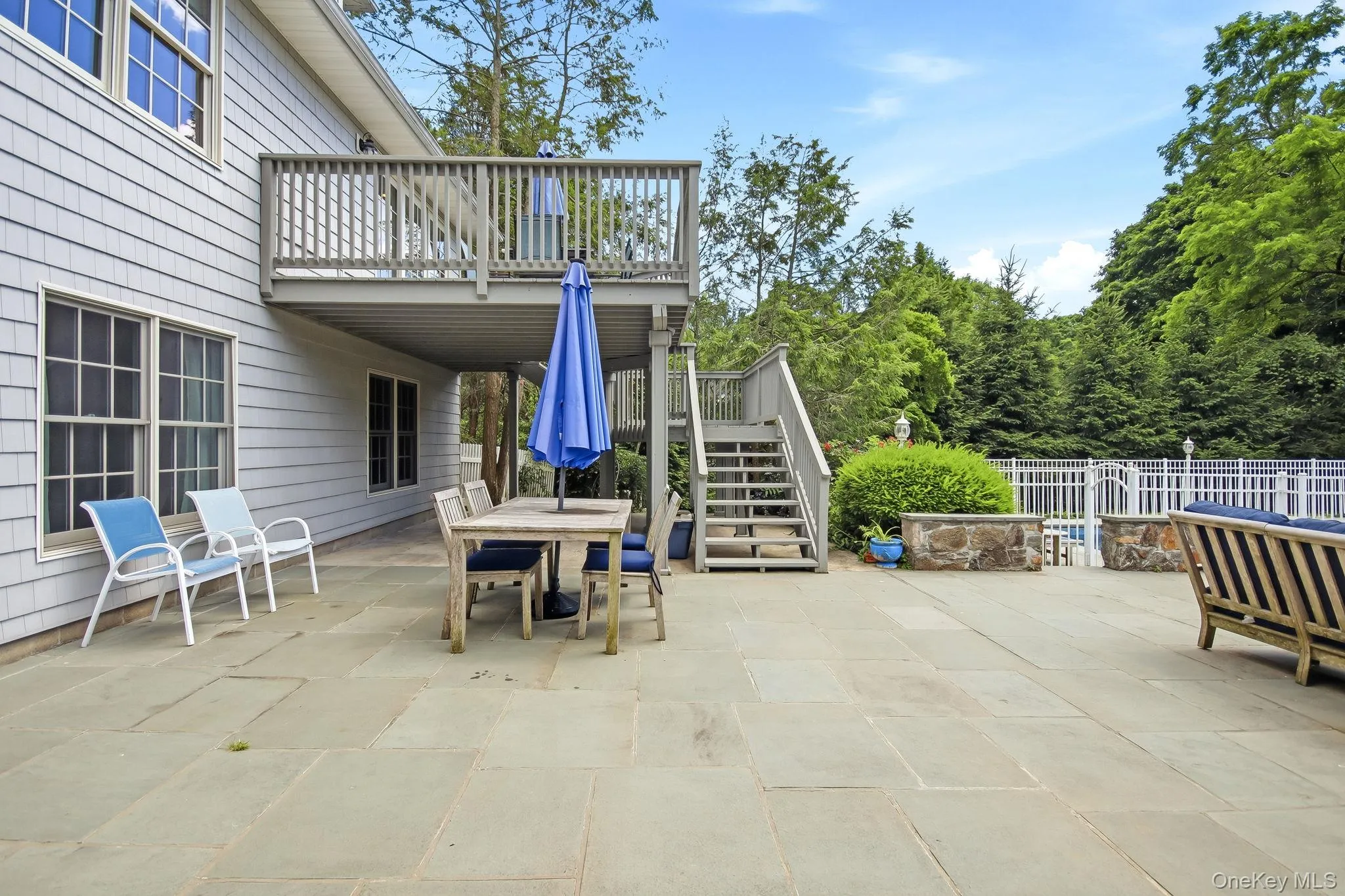 Expansive patio with a multi-level deck, featuring a fenced area and mature surrounding trees Expansive patio with a multi-level deck, featuring a fenced area and mature surrounding trees