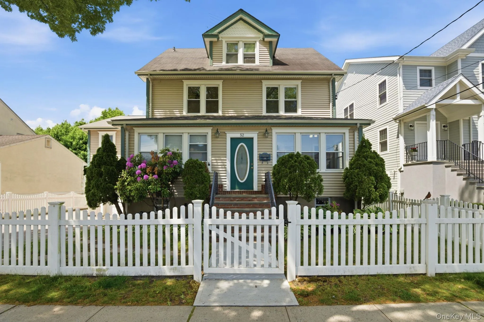 Traditional two-story residence with light-colored siding and a contrasting green-trimmed gable roof Traditional two-story residence with light-colored siding and a contrasting green-trimmed gable roof