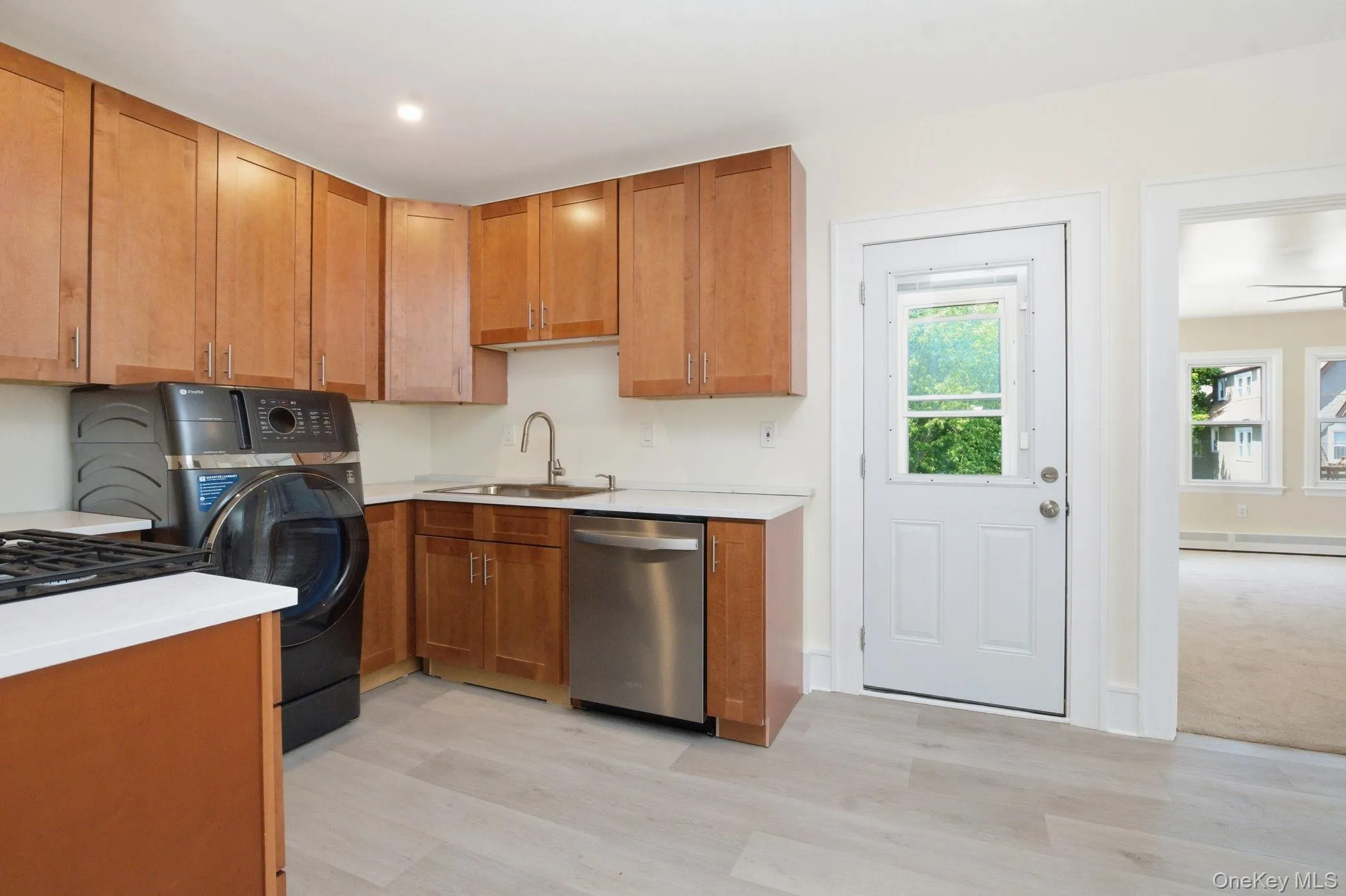 Kitchen featuring wood-finish cabinetry, light-toned countertops, a stainless steel sink, and light wood-look flooring Kitchen featuring wood-finish cabinetry, light-toned countertops, a stainless steel sink, and light wood-look flooring