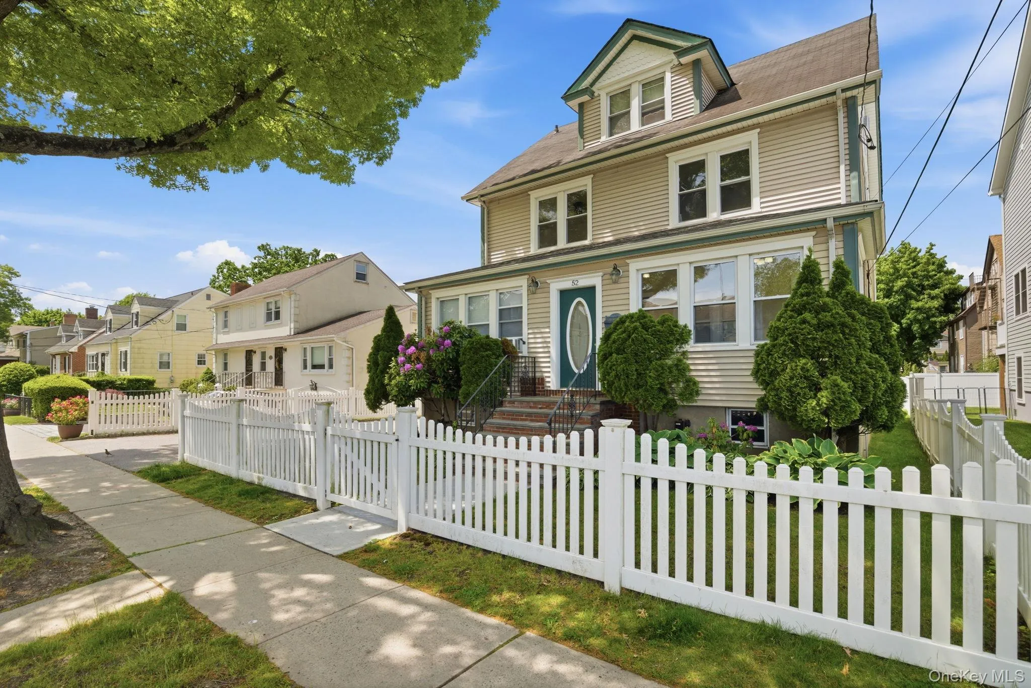 Two-story residence featuring light-colored siding and a contrasting dark roof Two-story residence featuring light-colored siding and a contrasting dark roof