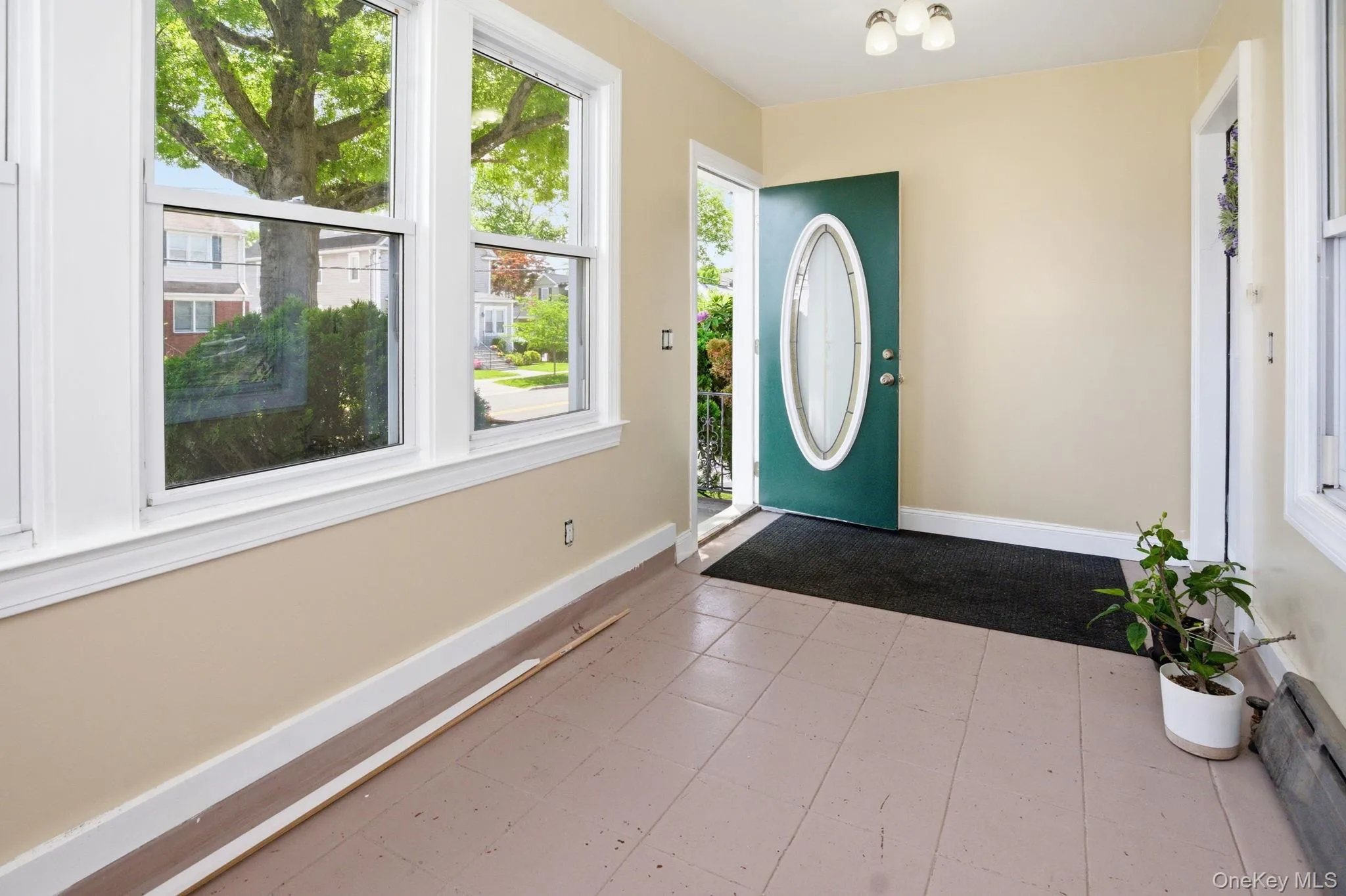 Entry area featuring a dark green entry door with an oval glass insert, multiple windows with white trim, light-colored walls, and a ceiling-mounted light fixture Entry area featuring a dark green entry door with an oval glass insert, multiple windows with white trim, light-colored walls, and a ceiling-mounted light fixture
