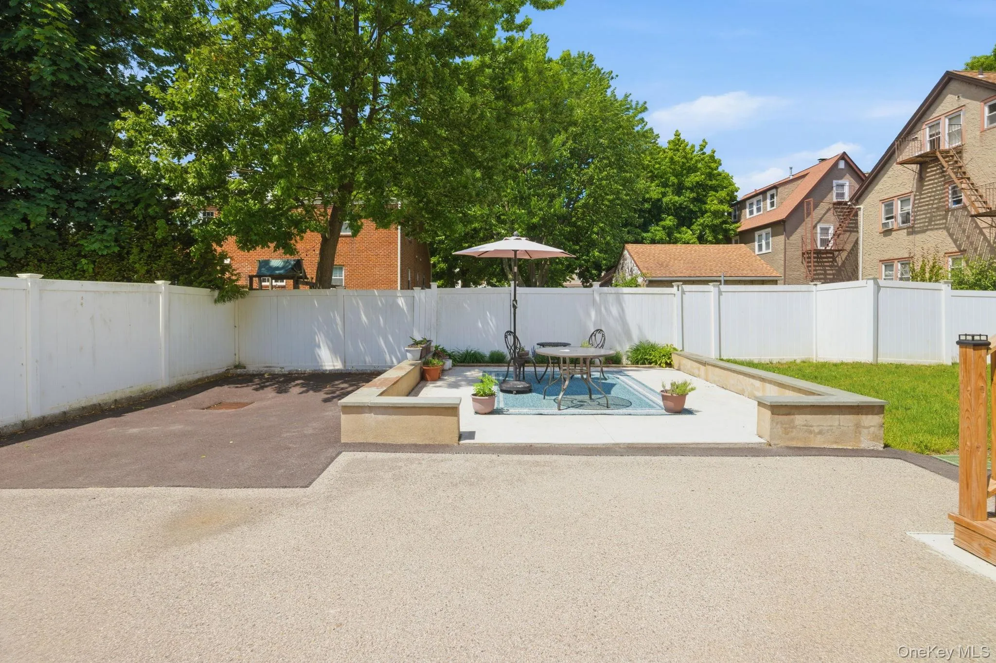 Expansive outdoor space featuring a textured light-colored ground surface, a defined concrete patio area, and a dark paved section Expansive outdoor space featuring a textured light-colored ground surface, a defined concrete patio area, and a dark paved section