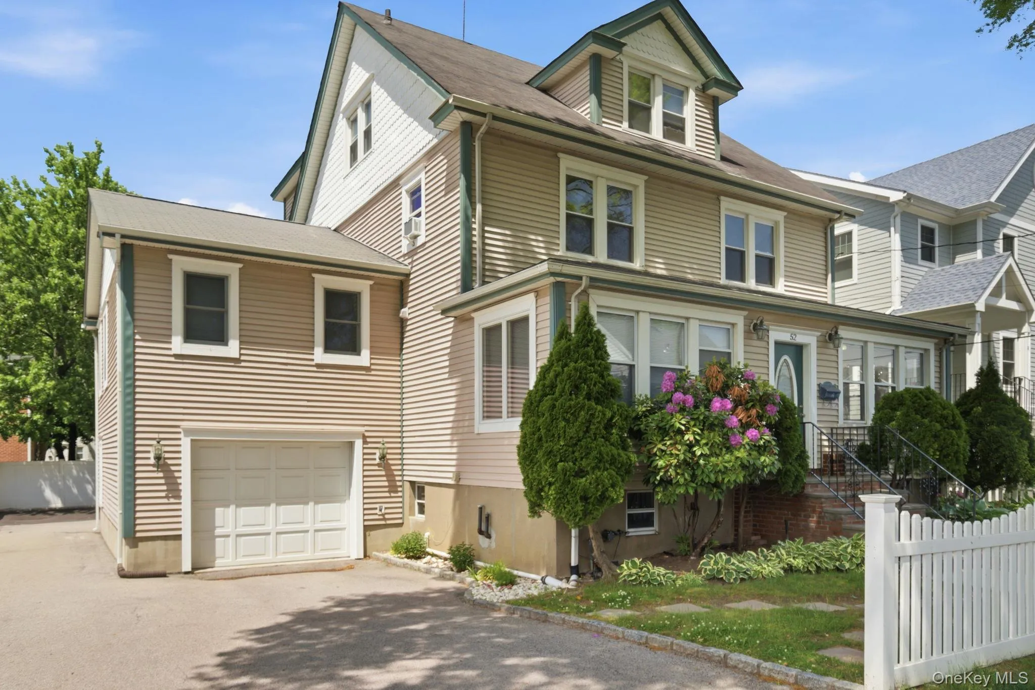 Two-story residence featuring light-toned horizontal siding with green trim accents and a dormer Two-story residence featuring light-toned horizontal siding with green trim accents and a dormer