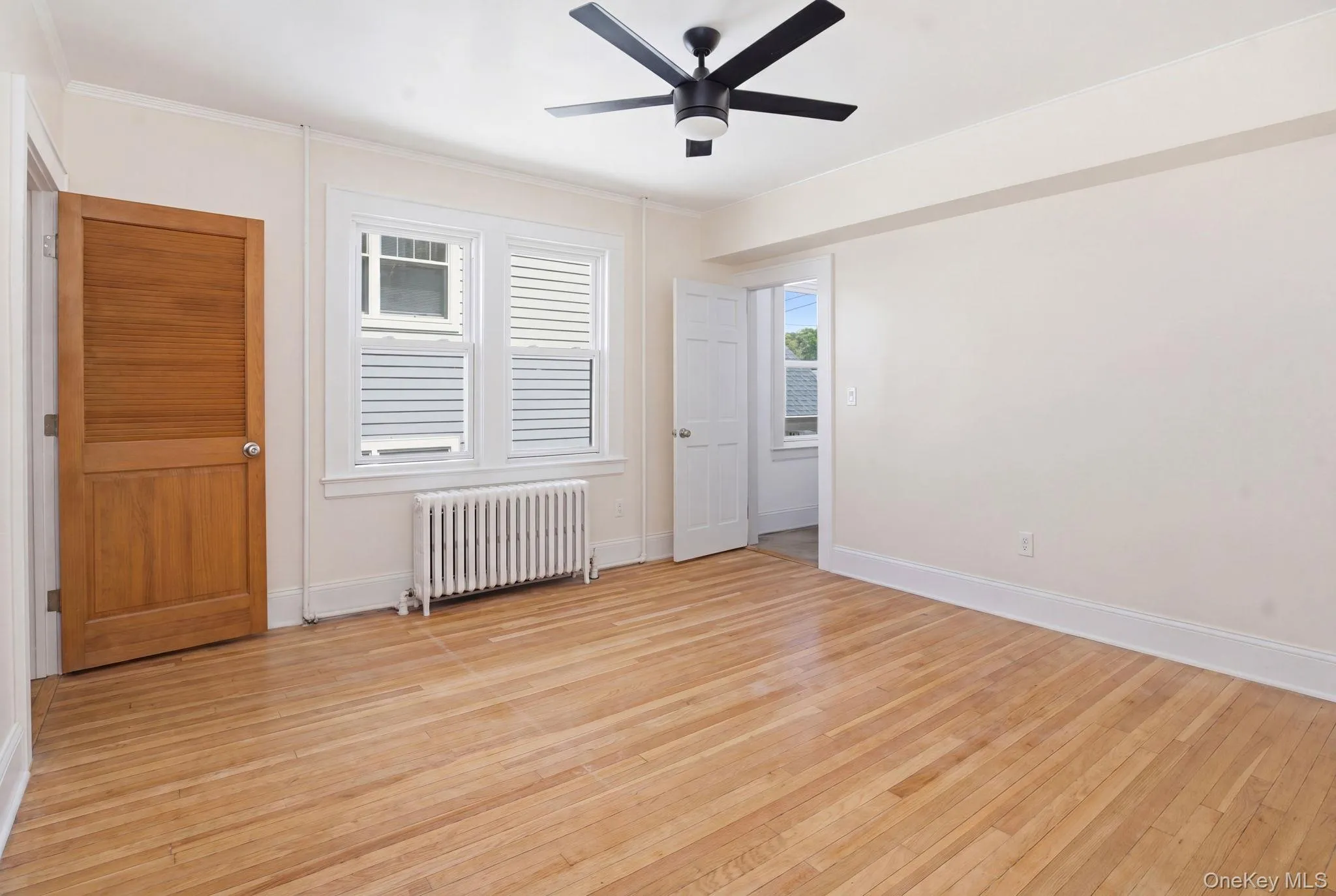 Light wood-finish flooring throughout, featuring a modern black ceiling fan with integrated lighting Light wood-finish flooring throughout, featuring a modern black ceiling fan with integrated lighting