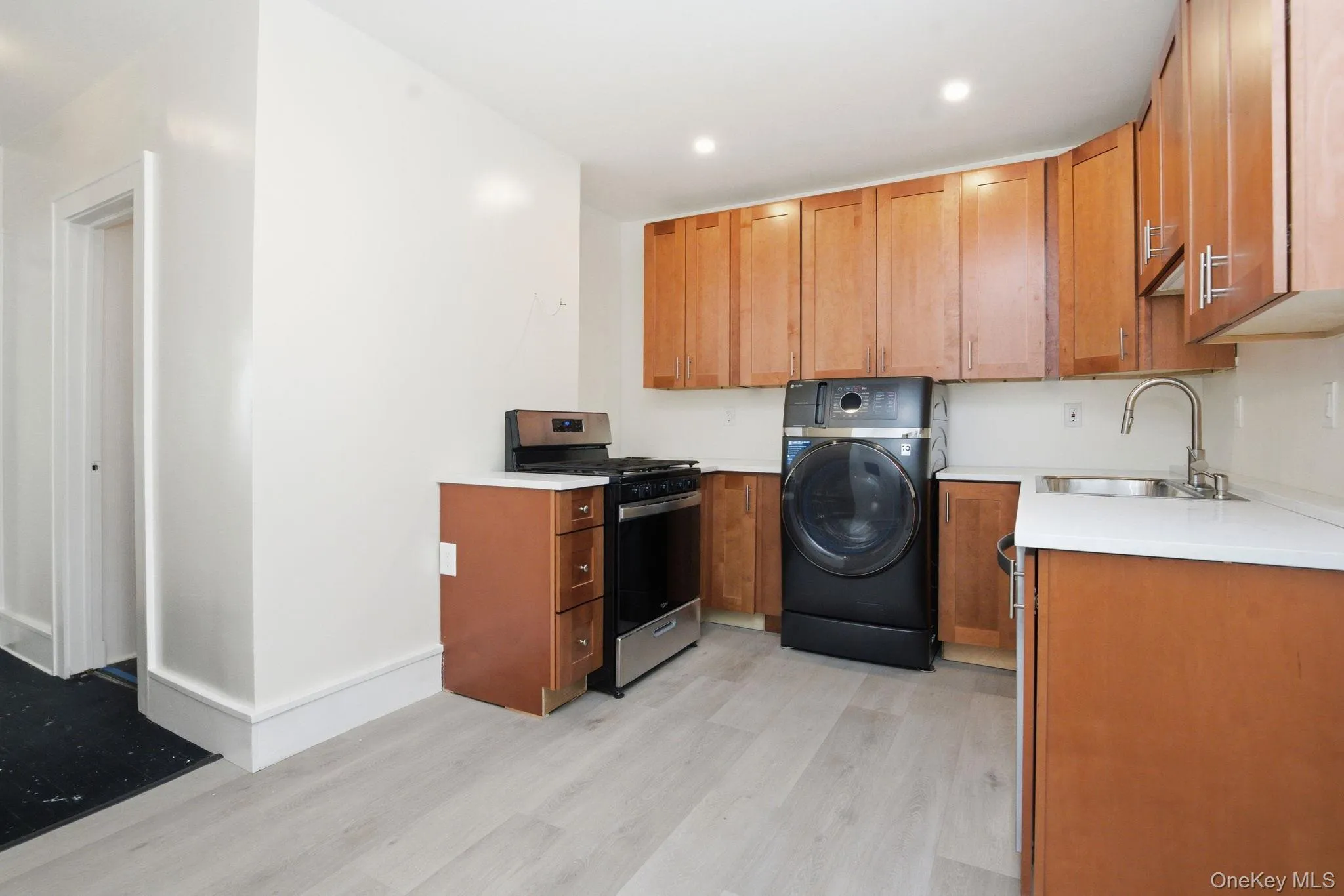 Kitchen area featuring light wood-finish flooring, brand new white quartz countertops, and wood cabinetry Kitchen area featuring light wood-finish flooring, brand new white quartz countertops, and wood cabinetry