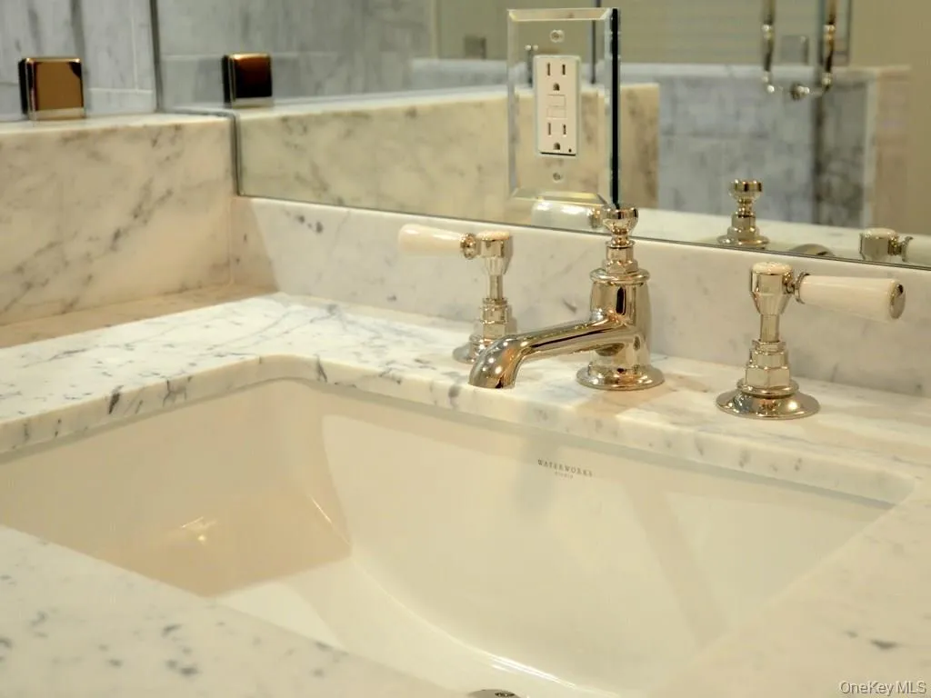 Primary bath sink detail with marble countertops and Waterworks fixtures. Primary bath sink detail with marble countertops and Waterworks fixtures.