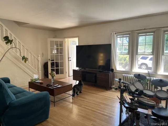 Hardwood flooring throughout a bright living space featuring a white painted staircase with a classic baluster design Hardwood flooring throughout a bright living space featuring a white painted staircase with a classic baluster design