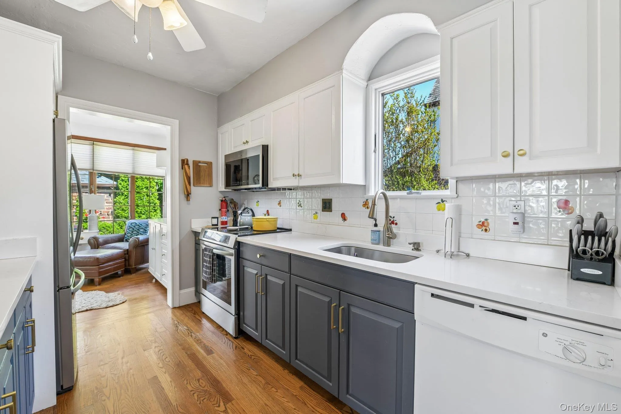 Kitchen featuring two-tone cabinetry, stainless steel appliances, and wood-finish flooring Kitchen featuring two-tone cabinetry, stainless steel appliances, and wood-finish flooring