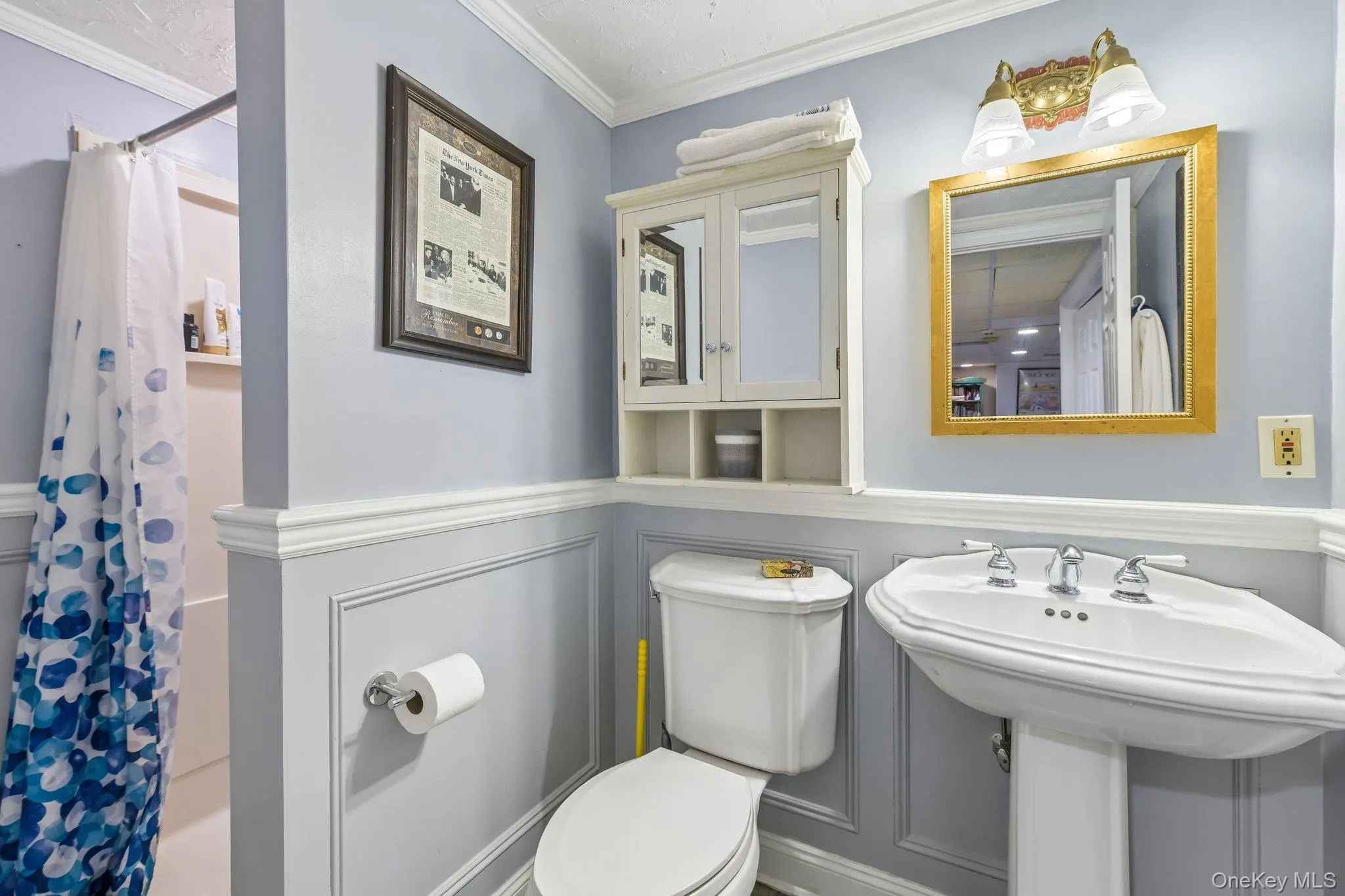 Bathroom featuring a pedestal sink, wainscoting, wall-mounted medicine cabinet, and a shower/tub combination Bathroom featuring a pedestal sink, wainscoting, wall-mounted medicine cabinet, and a shower/tub combination