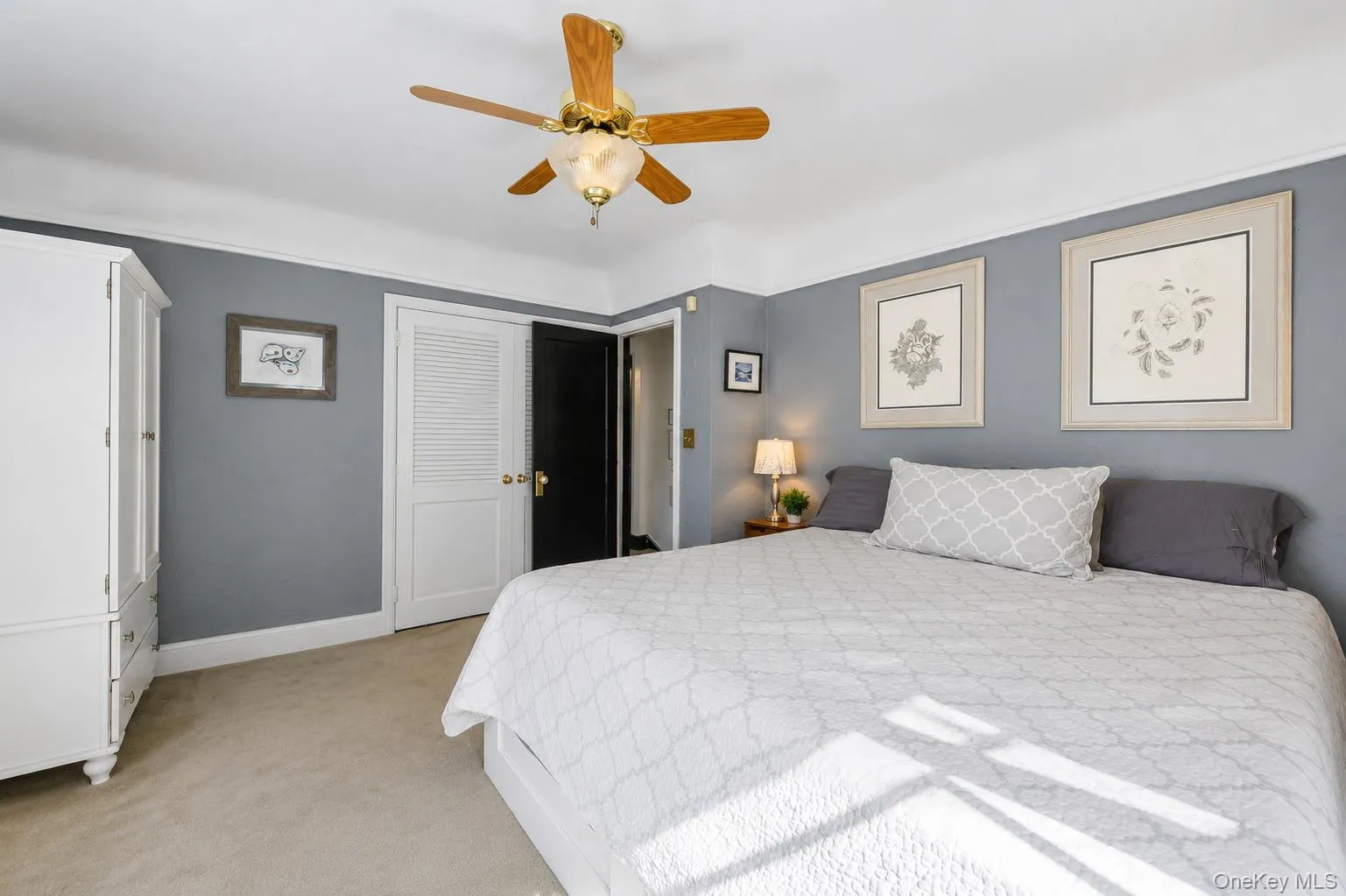 Carpeted bedroom featuring a ceiling fan, crown molding, and a built-in closet with louvered bi-fold doors Carpeted bedroom featuring a ceiling fan, crown molding, and a built-in closet with louvered bi-fold doors