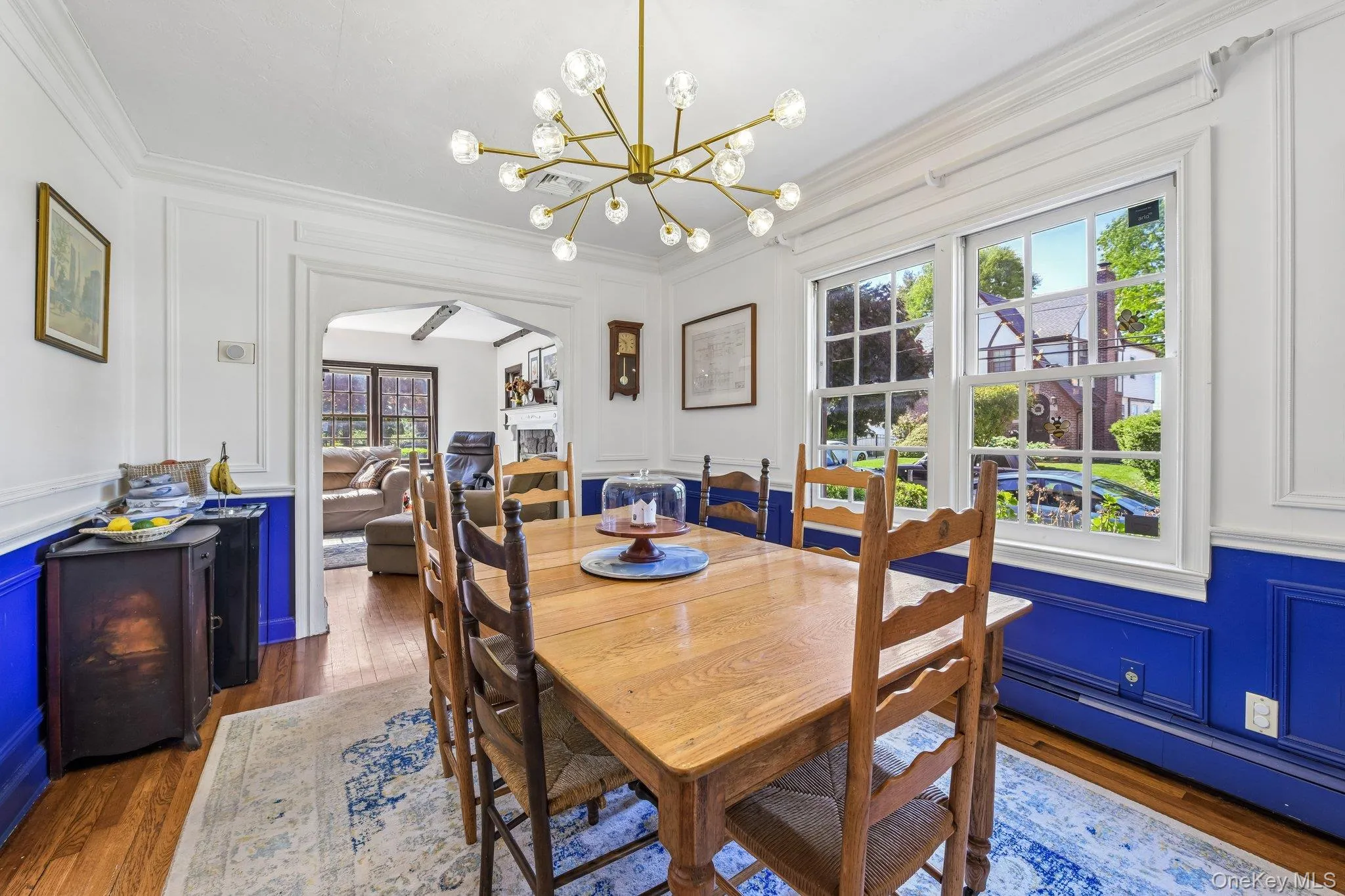 Formal dining area featuring hardwood flooring, a contemporary sputnik chandelier, two large windows with grid patterns, and an arched doorway leading to an additional living space Formal dining area featuring hardwood flooring, a contemporary sputnik chandelier, two large windows with grid patterns, and an arched doorway leading to an additional living space