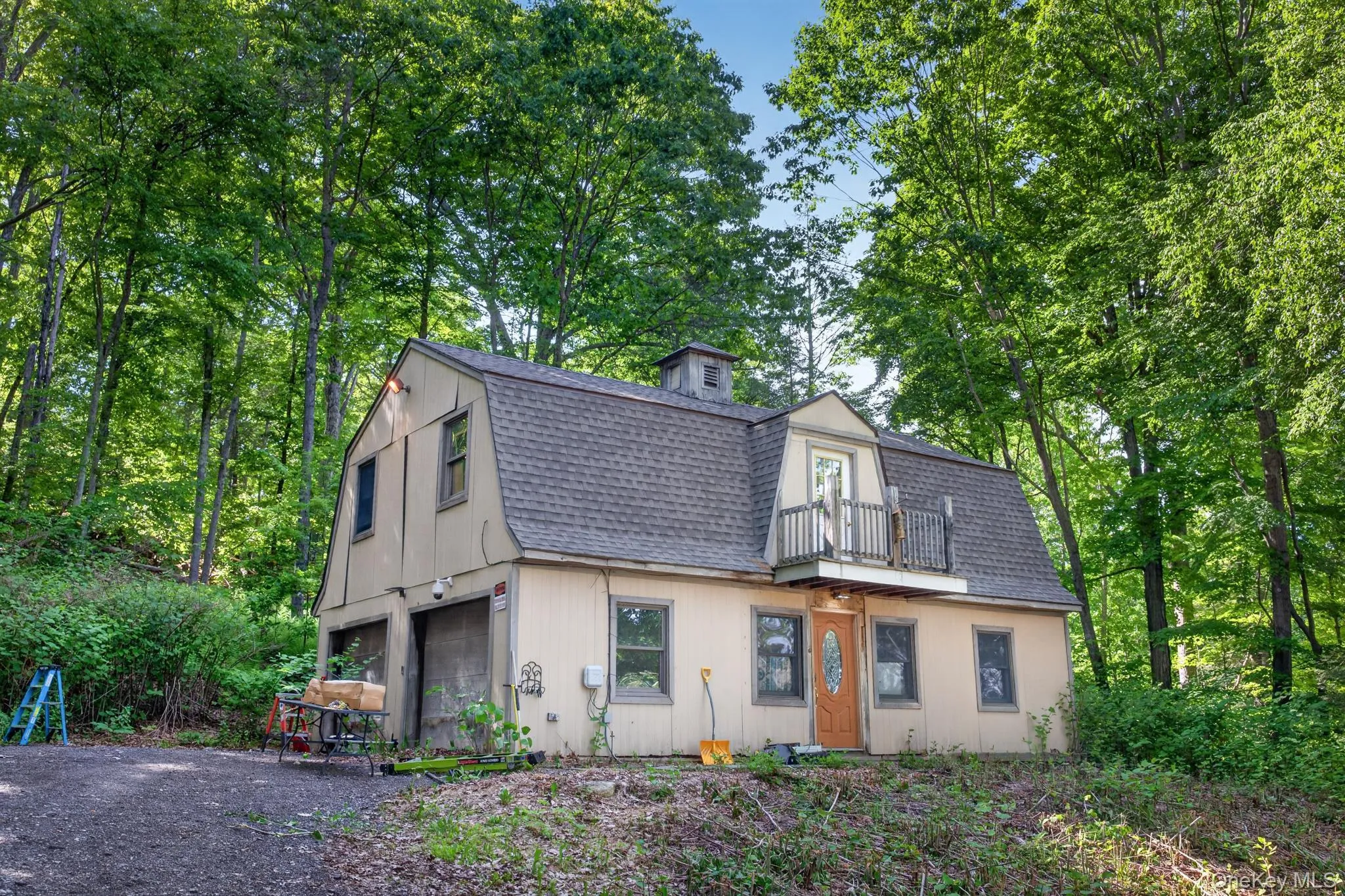 Gambrel-style residence featuring a dormer with a small balcony and wood railing Gambrel-style residence featuring a dormer with a small balcony and wood railing