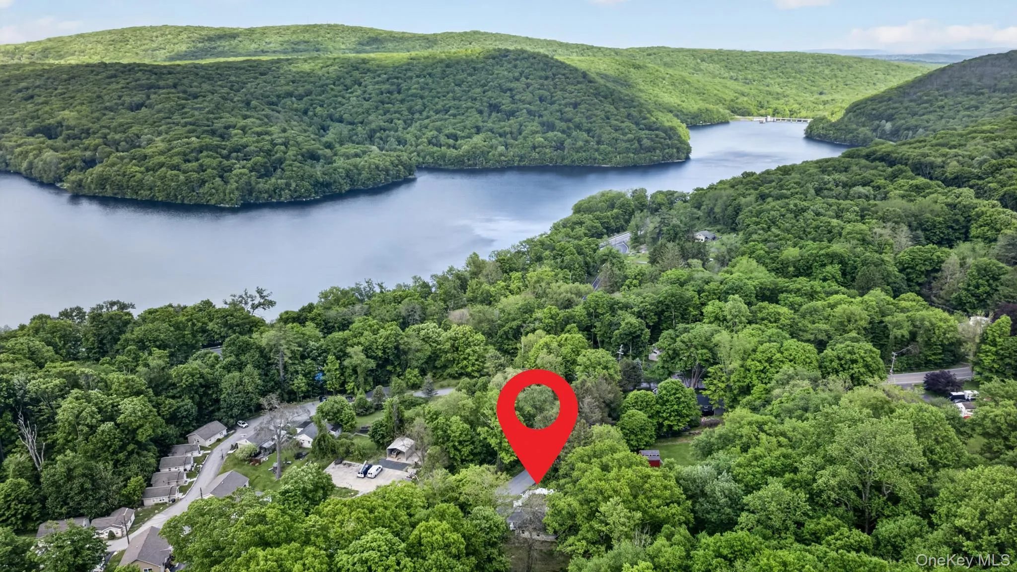 Aerial perspective showcasing a property surrounded by mature trees, with a prominent lake and verdant hills in the background Aerial perspective showcasing a property surrounded by mature trees, with a prominent lake and verdant hills in the background
