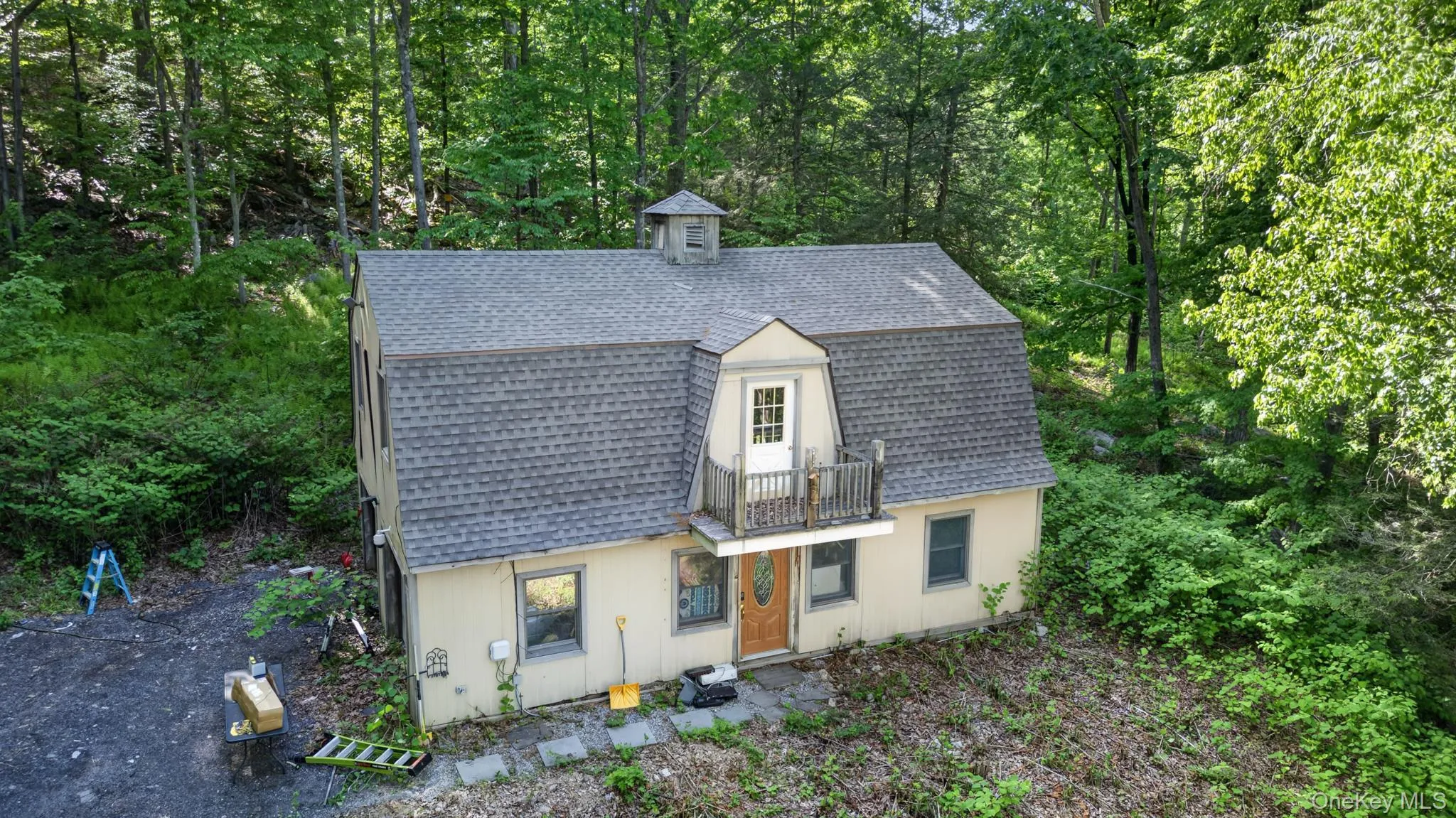 Gambrel roofline home featuring a cupola, upper-level balcony, and a natural tree-lined setting Gambrel roofline home featuring a cupola, upper-level balcony, and a natural tree-lined setting